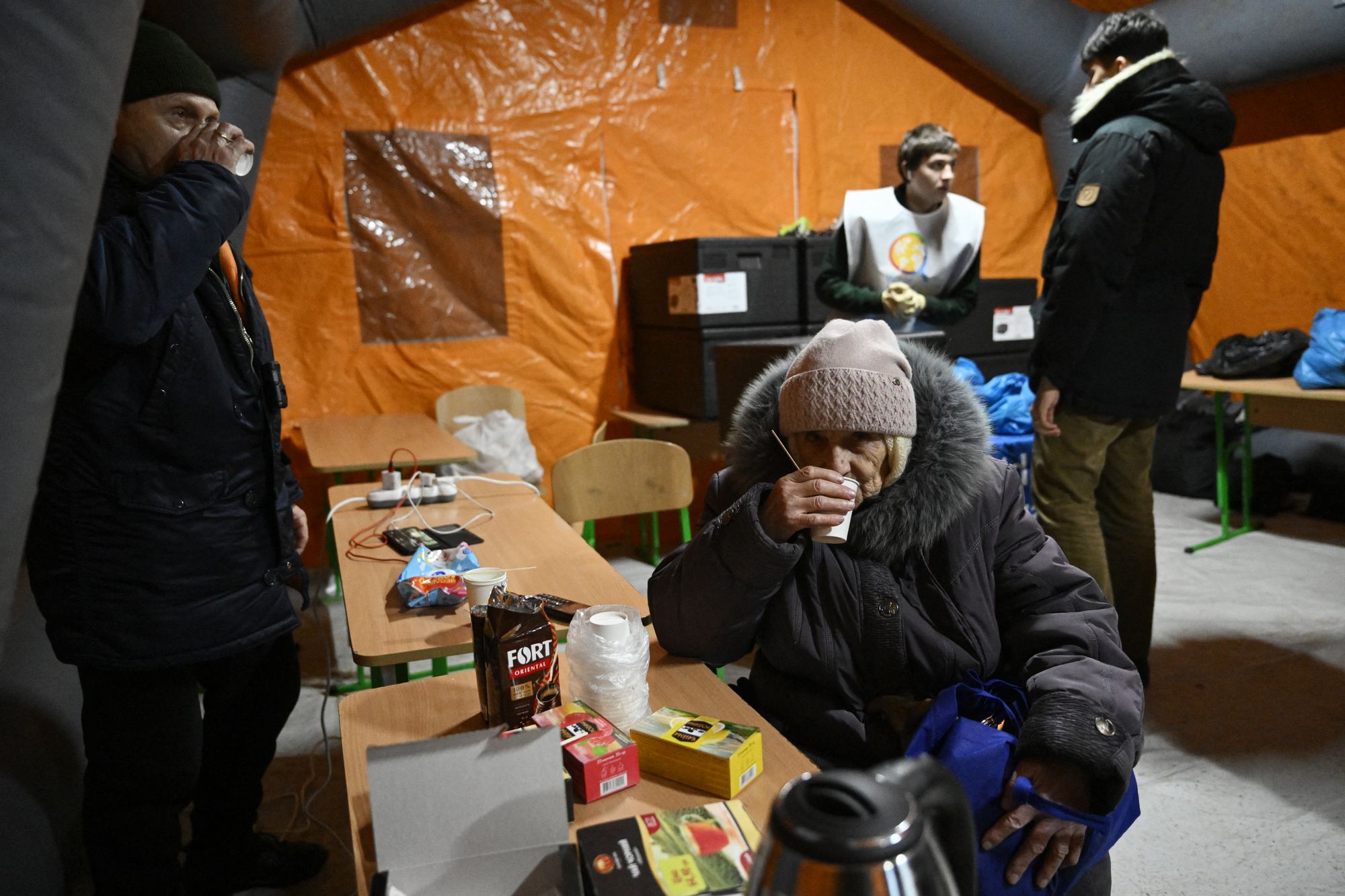 People warm themselves in an emergency service tent set up for those whose homes are without electricity or heating following Russian missile and drone attacks on Ukrainian energy infrastructure, in a residential neighborhood of Kyiv