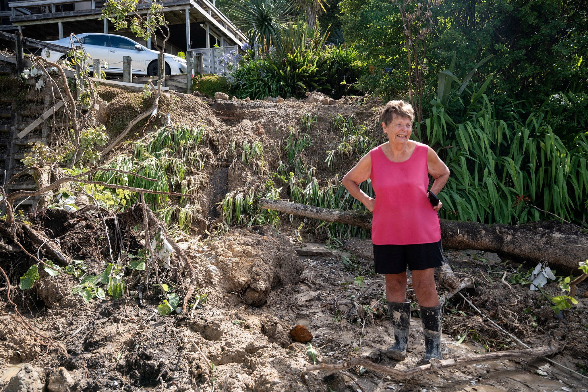 A resident from Tairua helps clean up a land slip following the recent storm that struck New Zealand