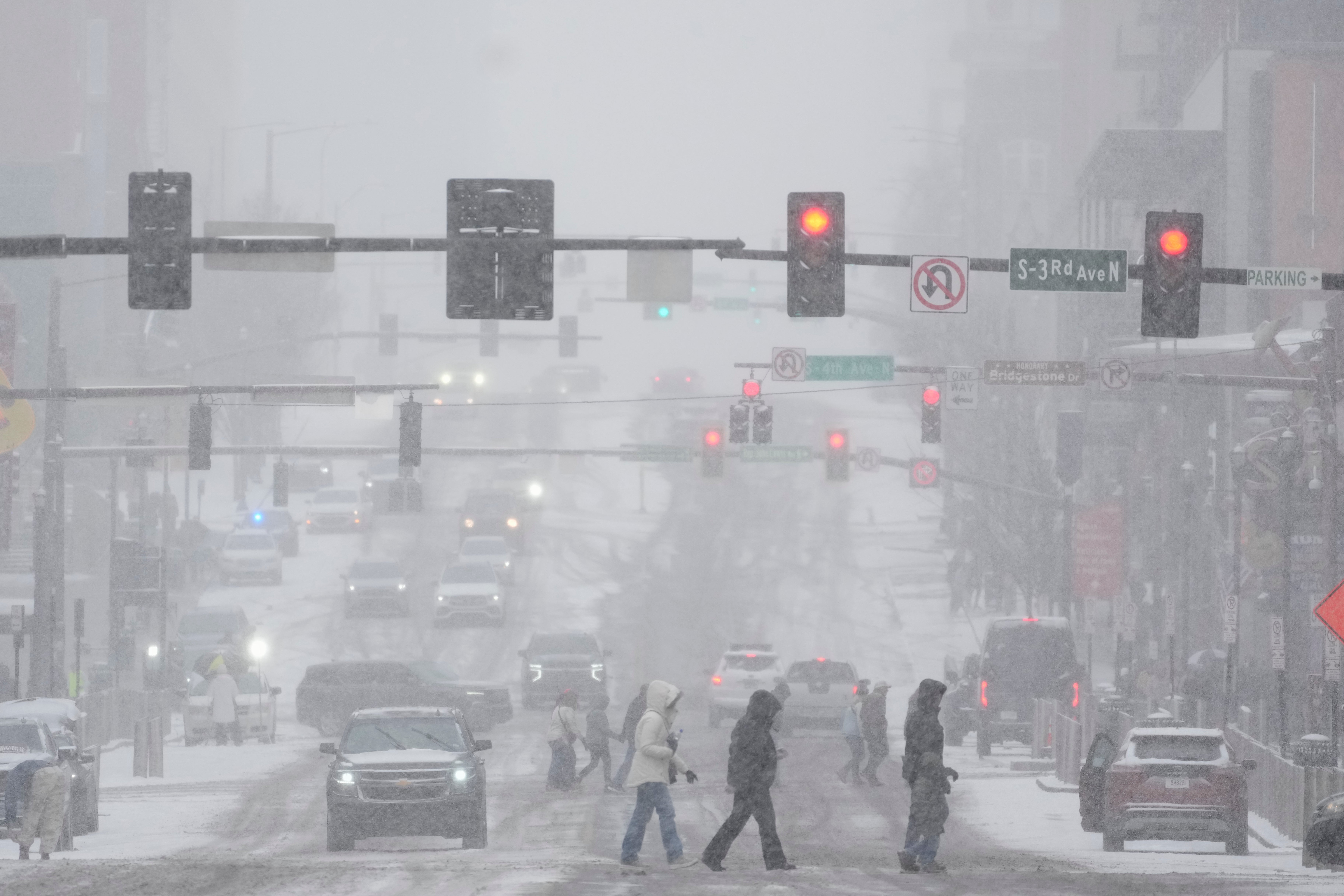 Pedestrians cross the street along Broadway during a winter storm Saturday, Jan. 24, 2026, in Nashville