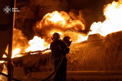 <p>A Ukrainian rescuer works to extinguish a burning petrol truck following an air attack in Kyiv</p>