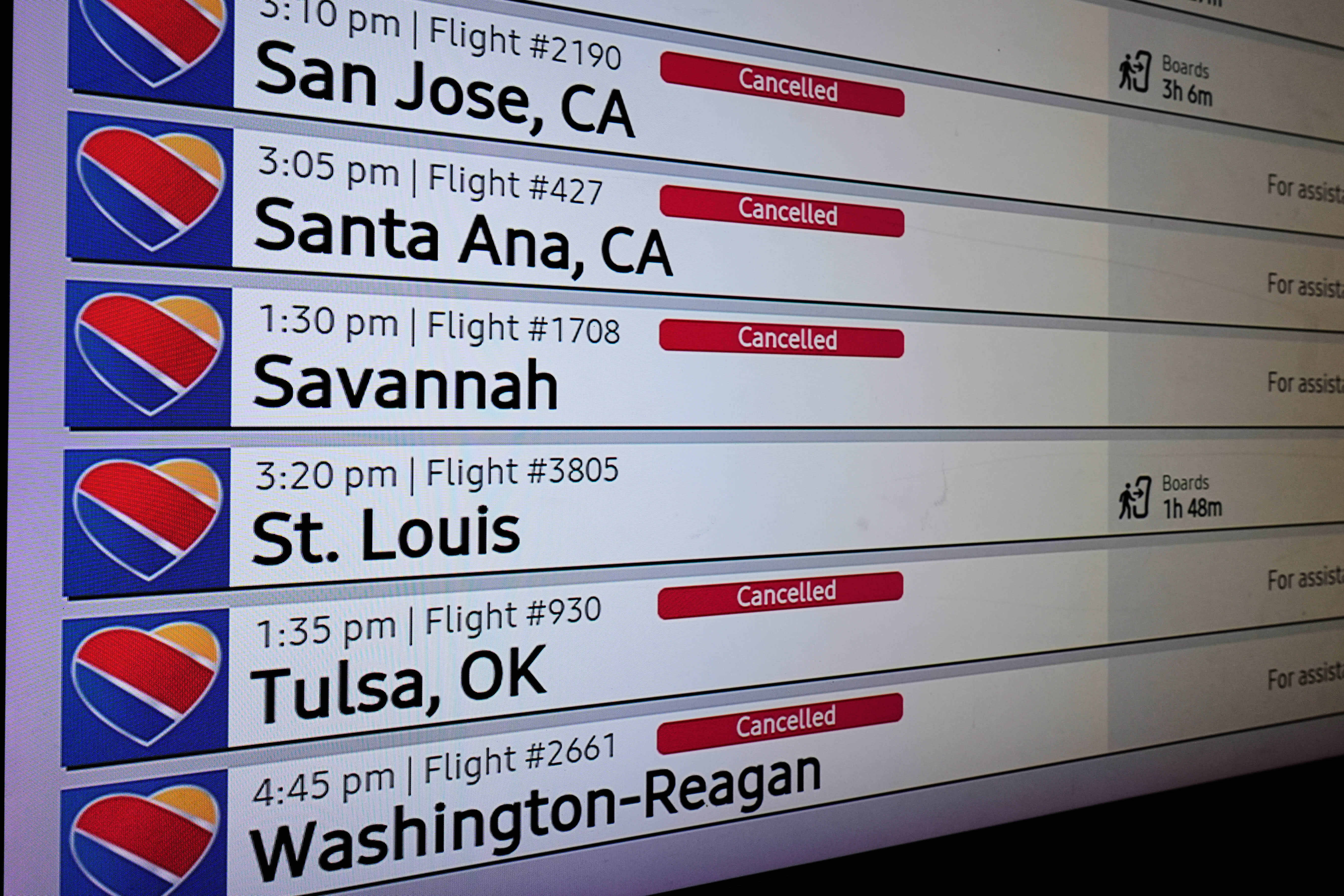 An arrivals and departures board reflects several flight cancellations in and out of Love Field Airport