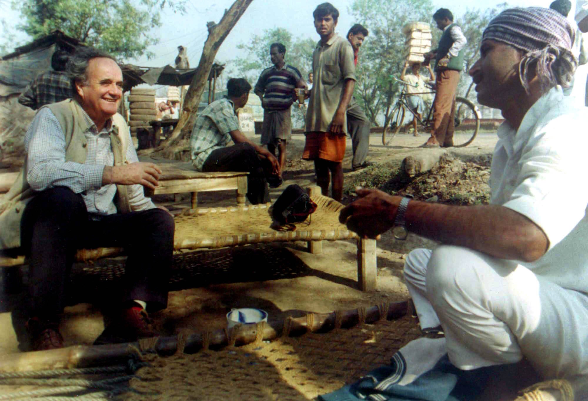 File. Mark Tully, left, chats with a truck driver at a highway teashop in Dankuni, 20km northwest of Kolkata, India, on 18 February 2002