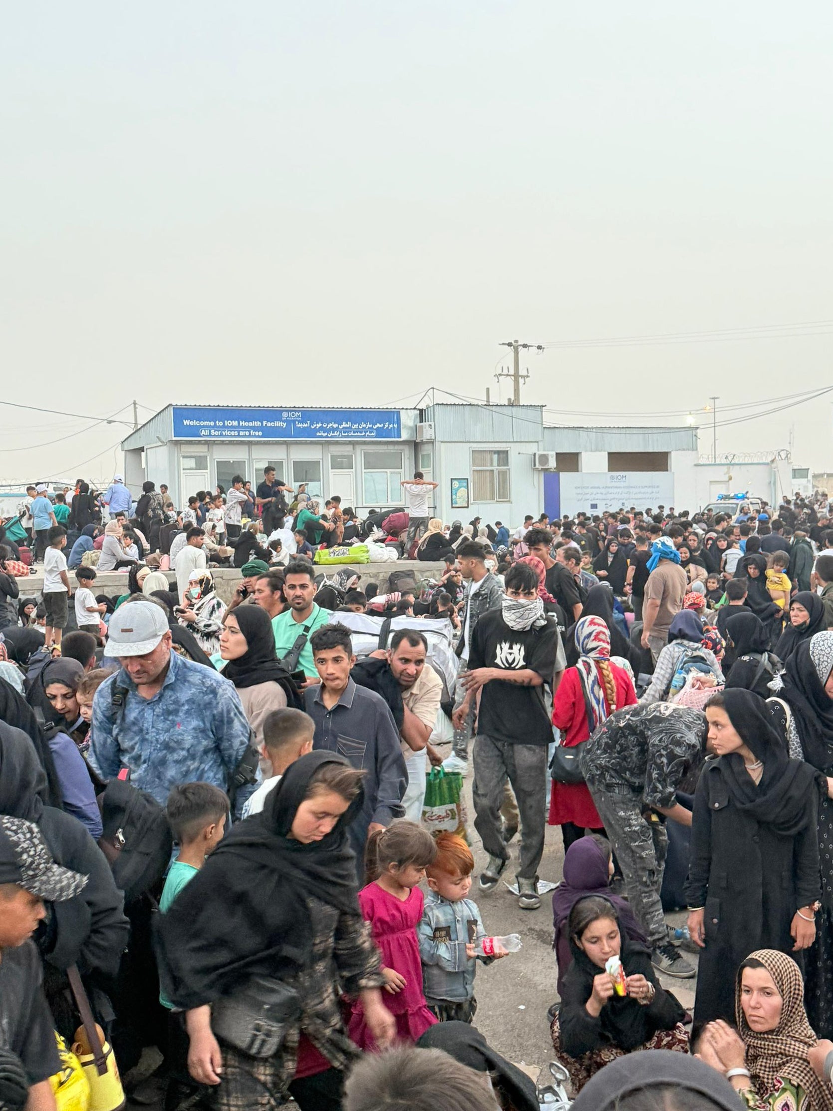 Returning Afghans queue at a border checkpoint in July 2025