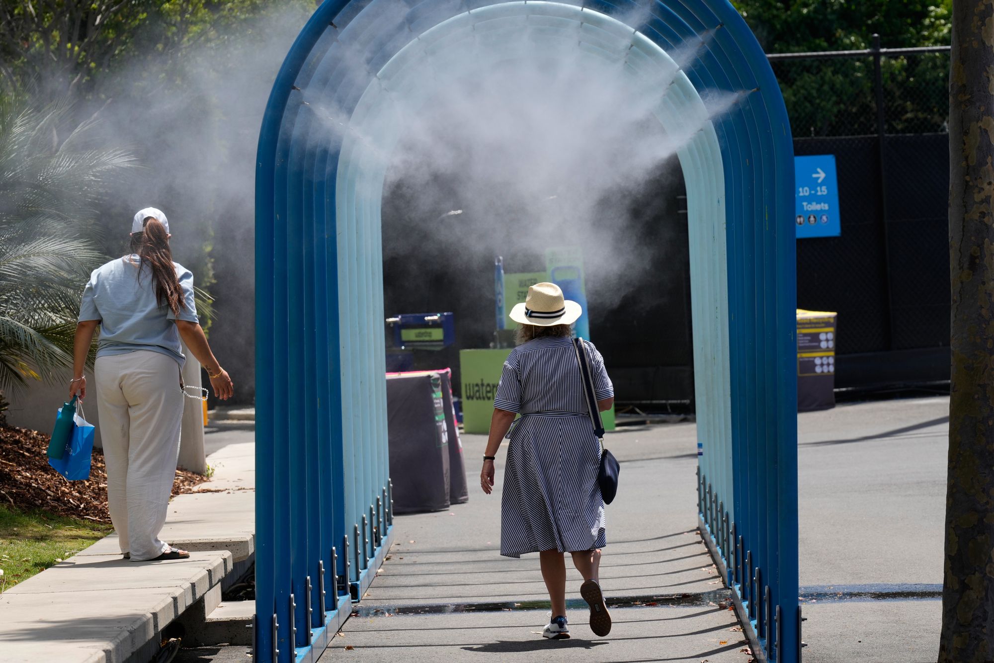 Fans walk through water misters at the Australian Open tennis championship in Melbourne, Australia