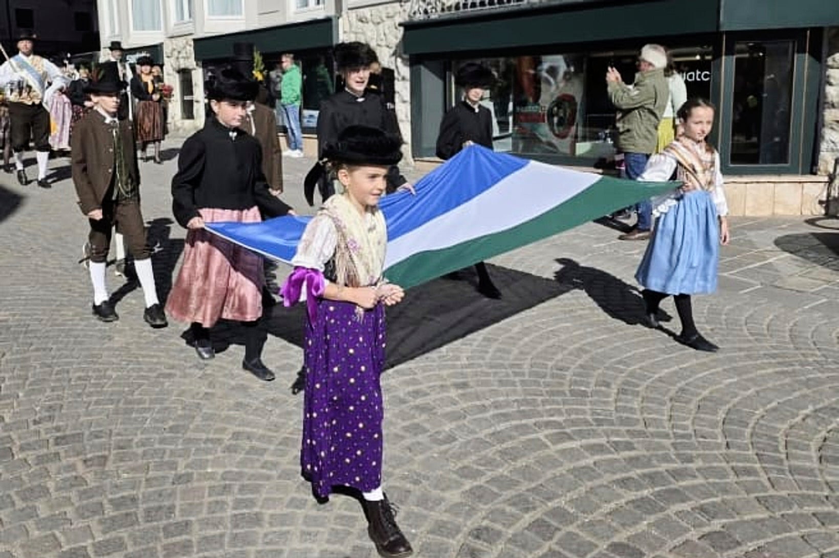 People carry a traditional Ladin flag during a parade through the streets of Cortina D'Ampezzo, northern Italy