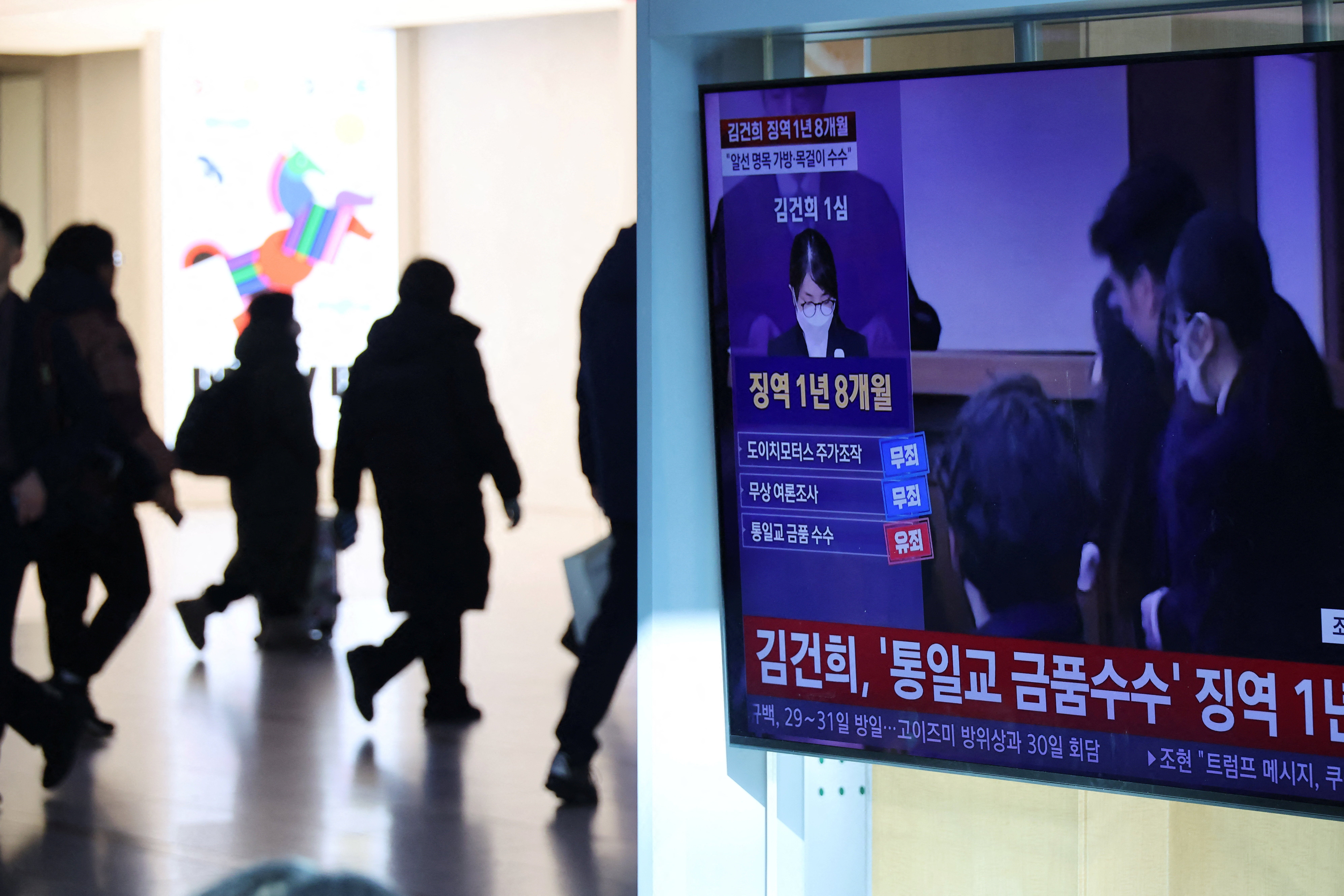 People walk past a TV broadcasting a news report on the sentencing trial of South Korean former first lady Kim Keon Hee in Seoul, South Korea, 28 January 2026
