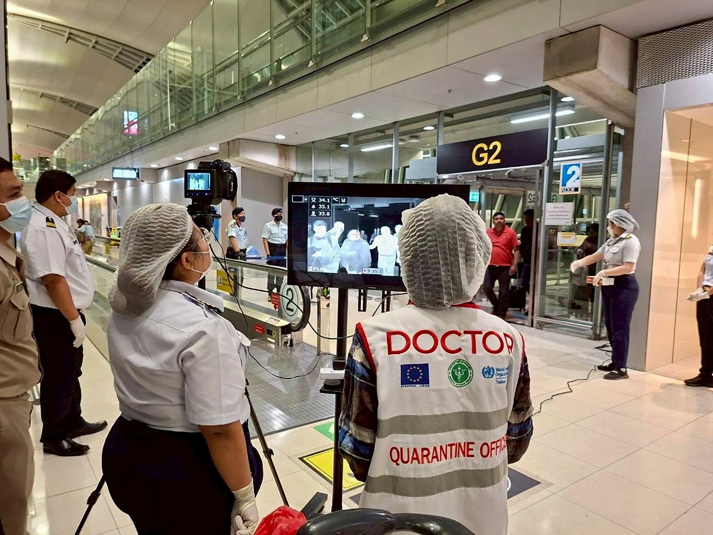 Airport health authorities wearing protective masks monitor passengers arriving at Suvarnabhumi international airport in Bangkok, Thailand
