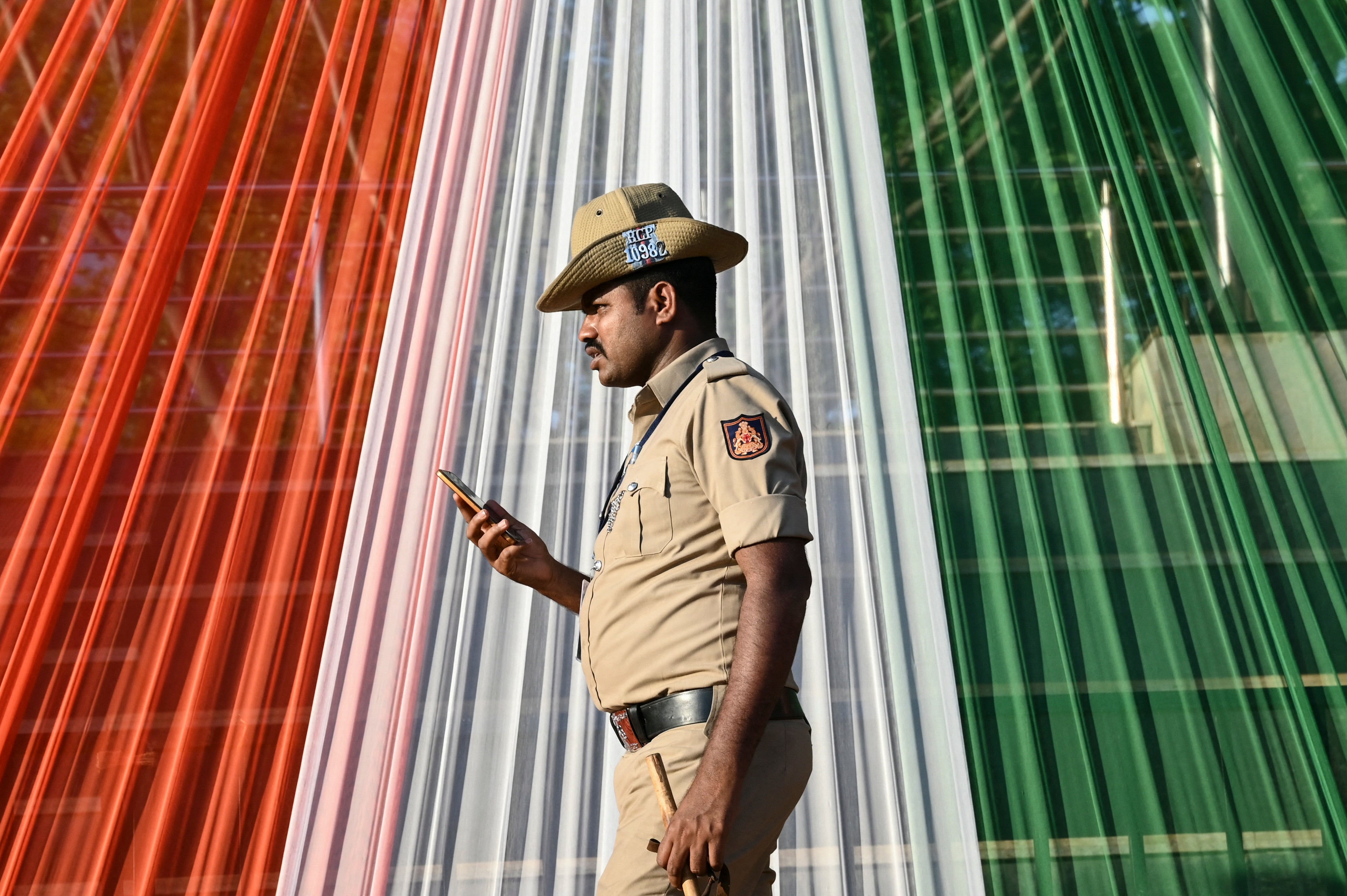 <p>File. Police officer checks his phone in Delhi, India</p>