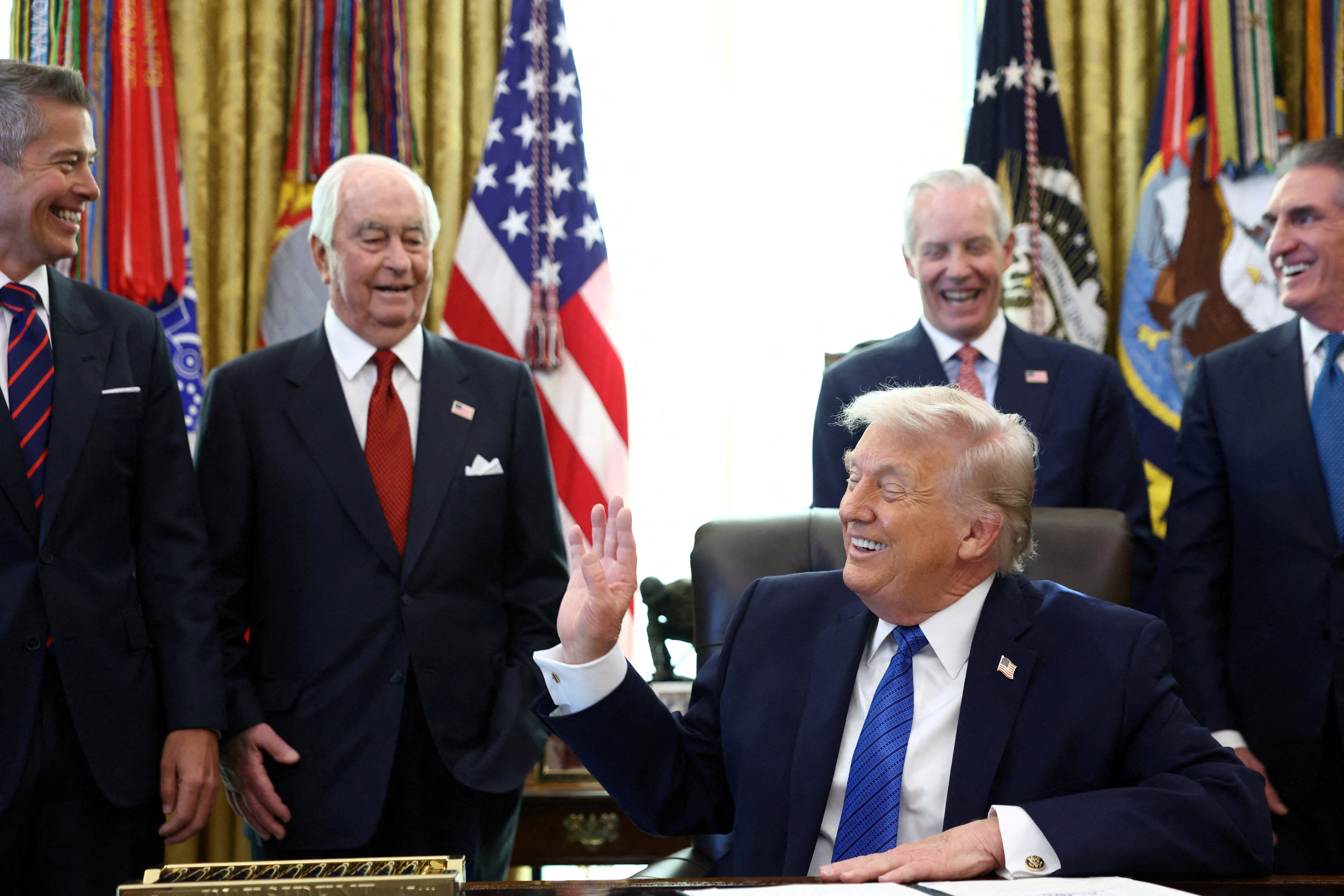 Roger Penske, businessman and former race car driver, U.S. Secretary of Transportation Sean Duffy, and U.S. Secretary of the Interior Doug Burgum, react as U.S. President Donald Trump speaks in the Oval Office on Jan. 30, 2026.