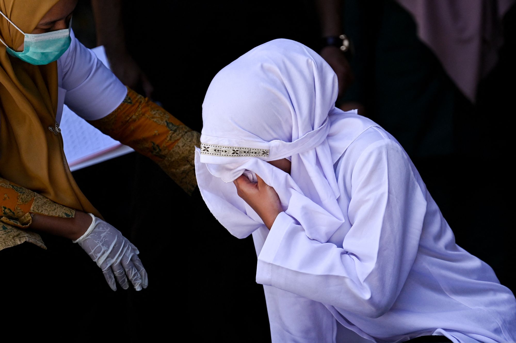 A woman accused of having sex outside marriage reacts after being publicly caned by a member of the Sharia police in Banda Aceh on 29 January 2026