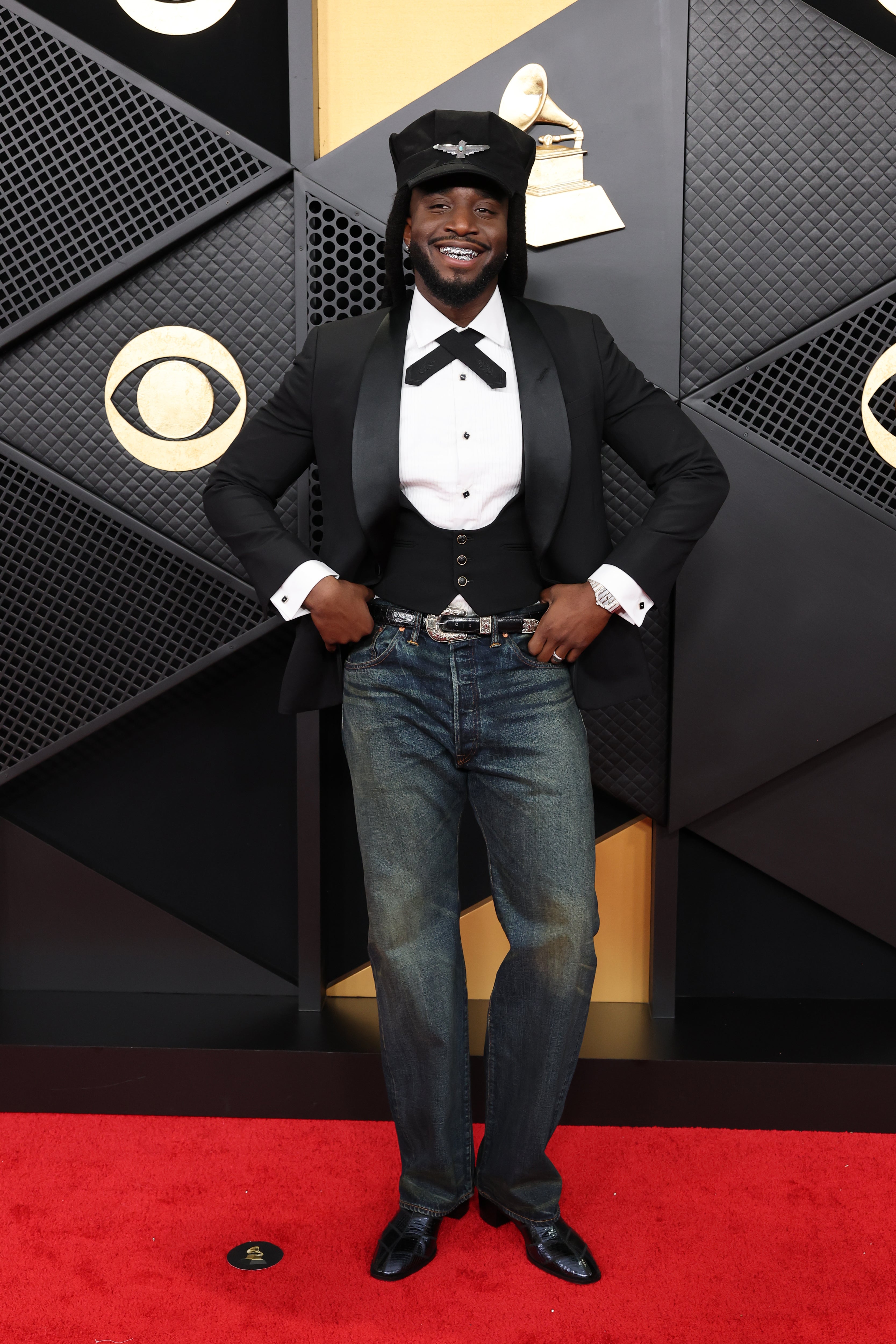 The ‘A Bar Song’ singer's mismatched outfit combined casual and black tie ensembles, with jeans and a flashy belt on the bottom, and a tuxedo jacket and pilot’s cap on top