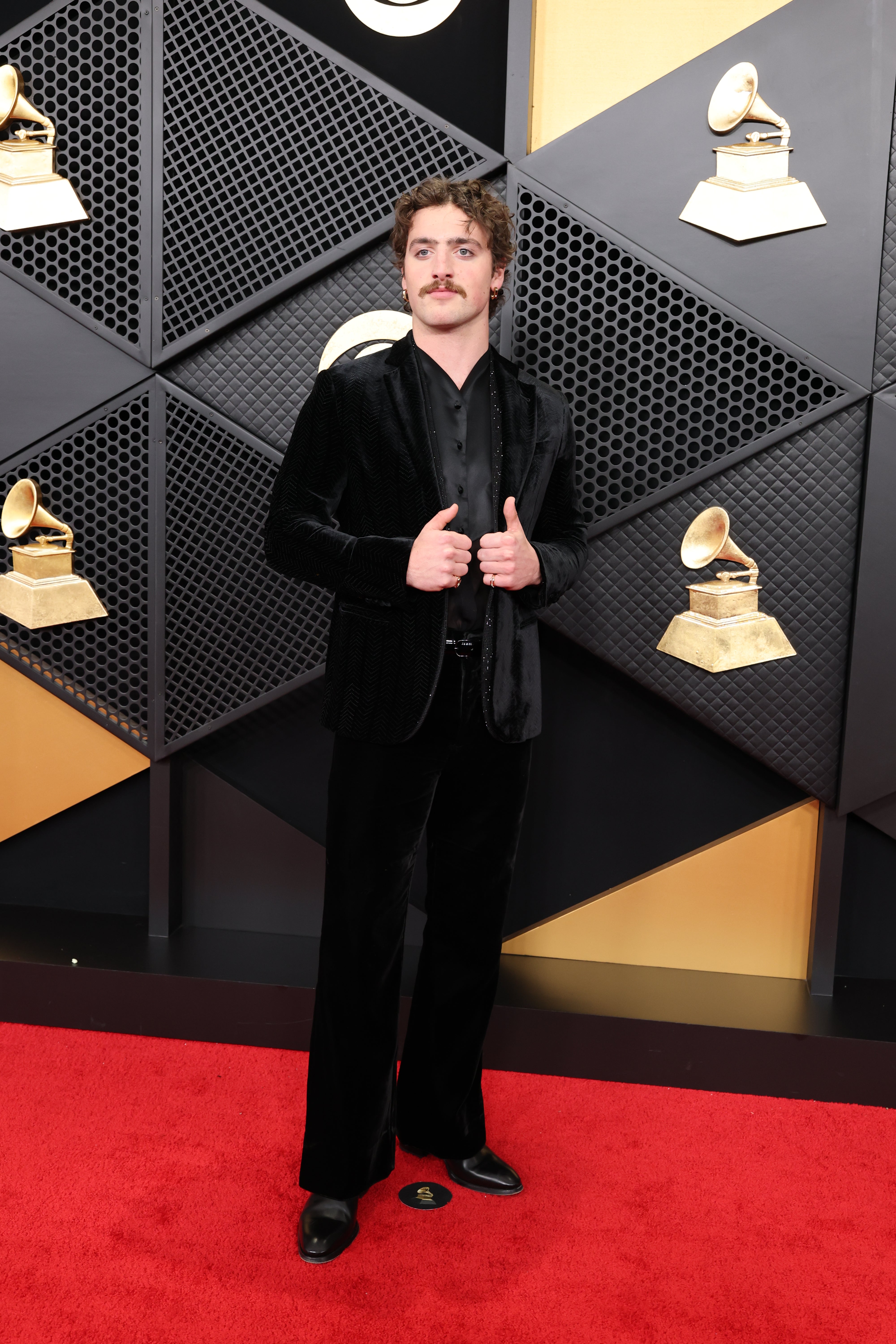 Benson Boone proved that an all-black outfit never goes out of style. He wore a classic black velvet coat, matching pants, and a see-through shirt