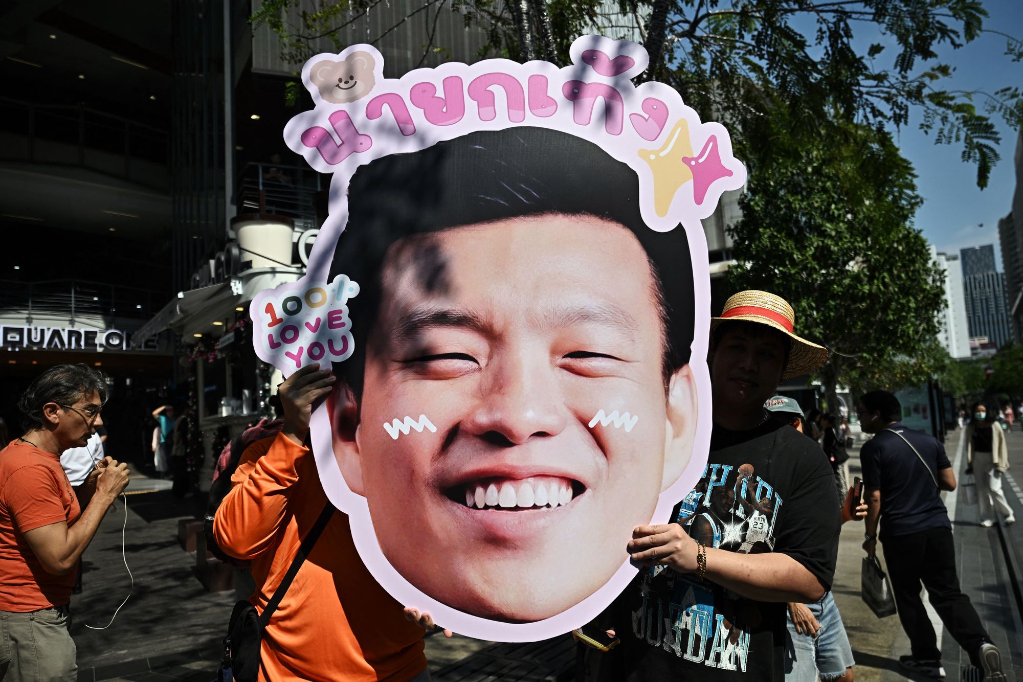 A supporter of the People's Party holds a likeness of prime ministerial candidate Natthaphong Ruengpanyawut in Bangkok