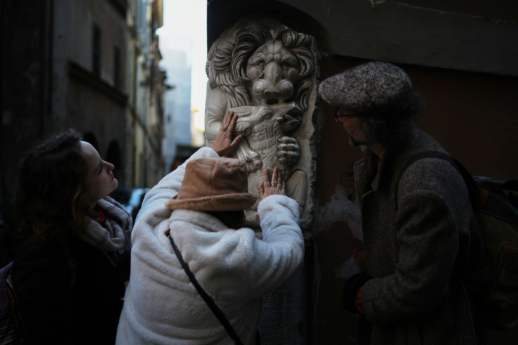 Francesca Inglese, who is blind, touches a marble relief on the corner of a building during an inclusive art tour in downtown Rome
