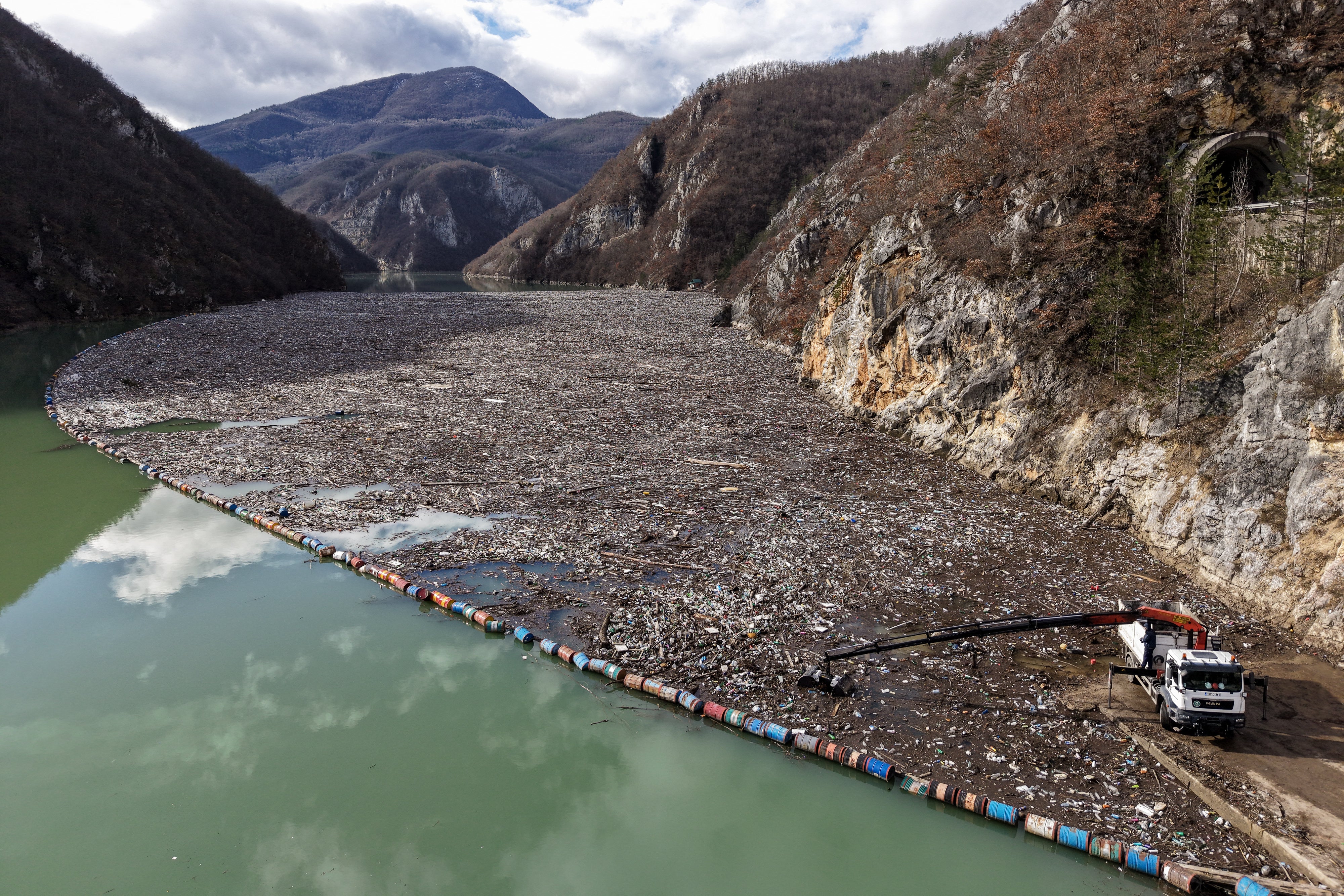 The sight recalls scenes from environmental disaster movies — an otherwise emerald green surface of river thickly covered with plastic bottles, pieces of wood or furniture, rusty barrels, home appliances or even dead animals