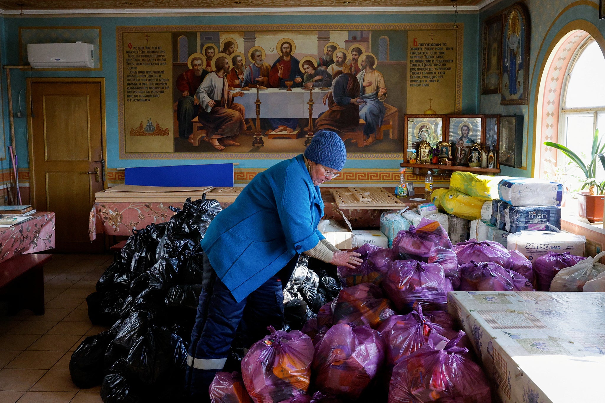 Volunteer Tatyana Tikhonova places plastic bags containing food and personal hygiene products in a church in the Luhansk region