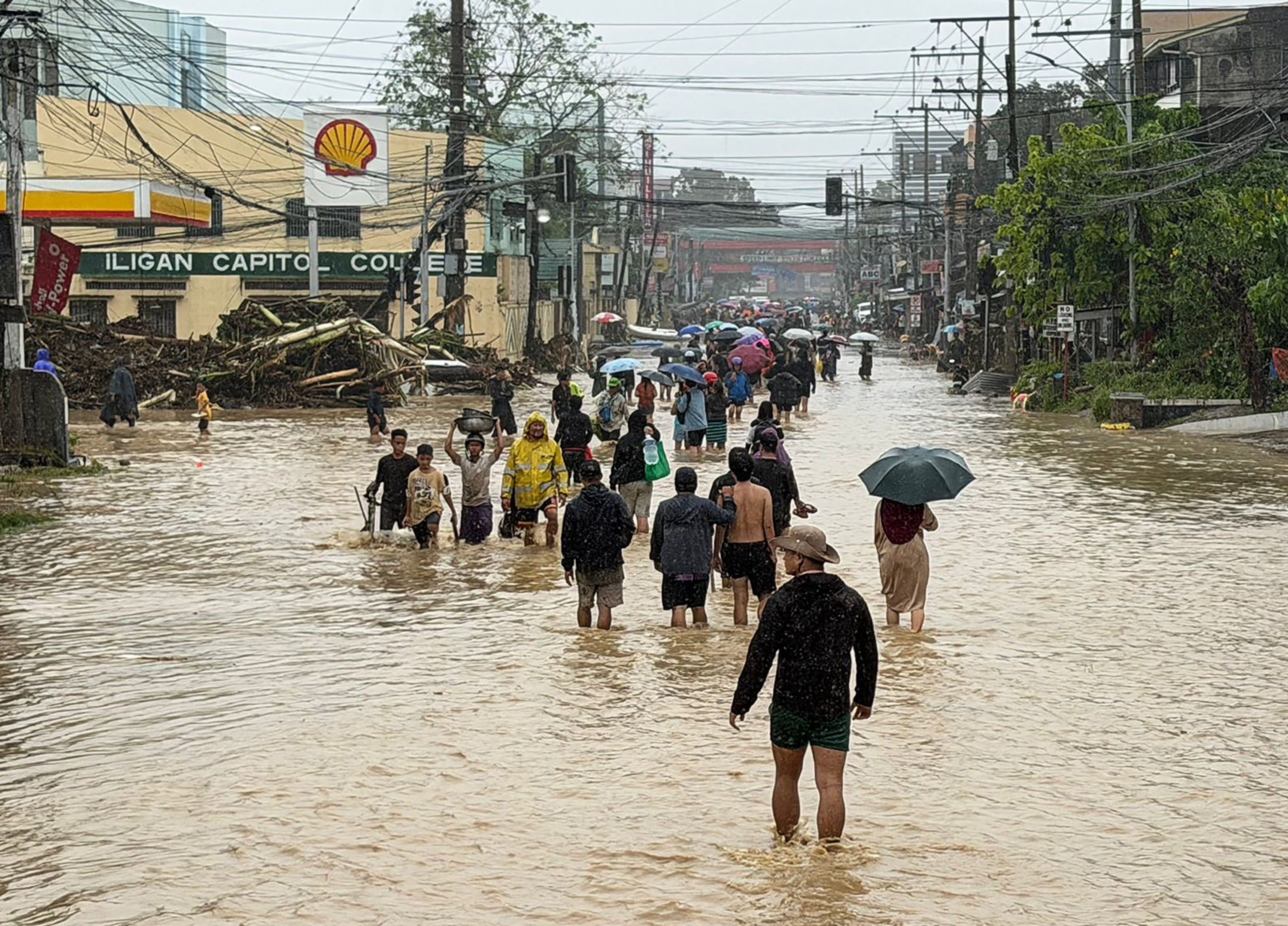 People wade through floodwaters brought by Tropical Storm Penha in Iligan, Lanao del Norte, Philippines