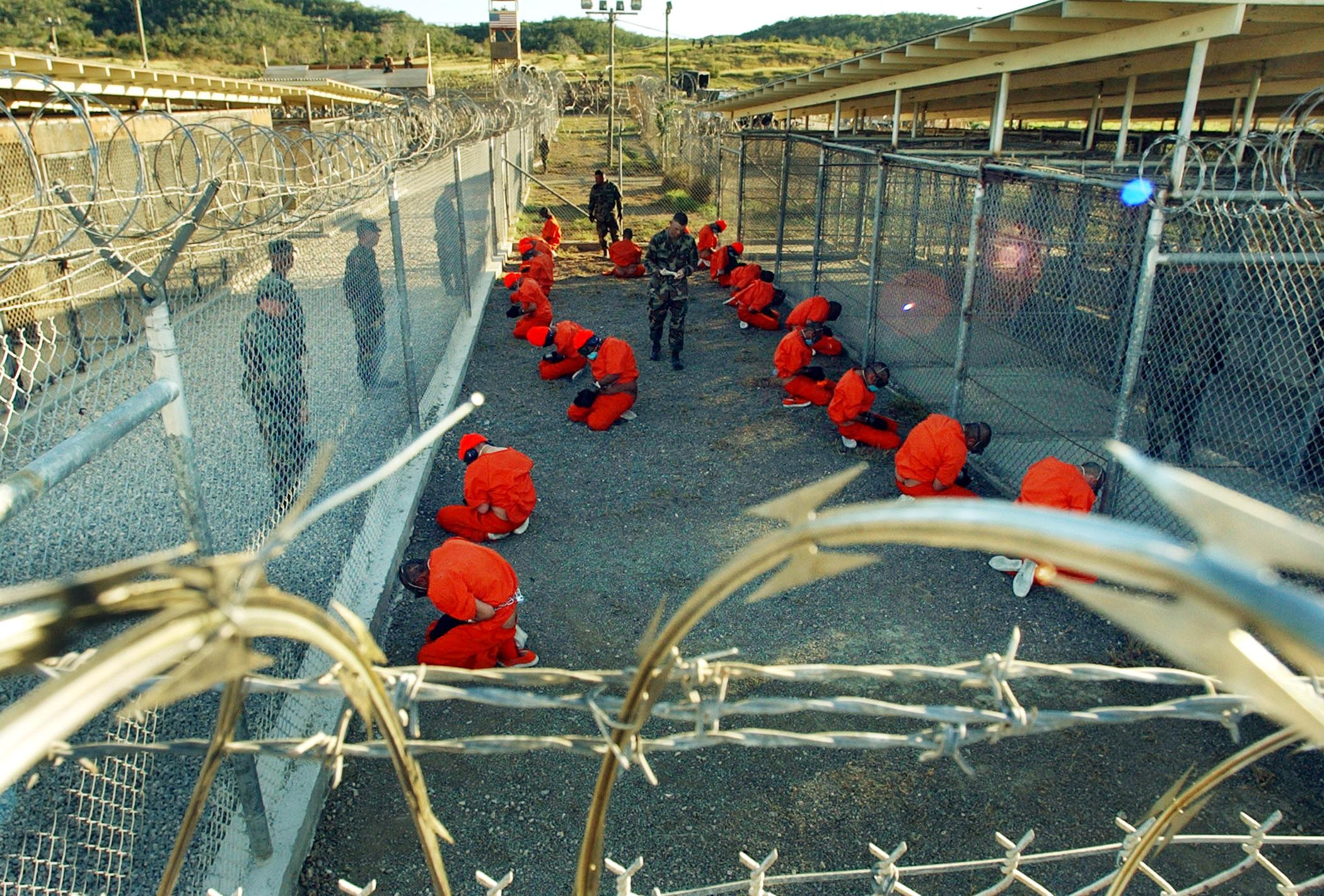 Al-Qaeda and Taliban detainees sit in a holding area under the surveillance of US military police at Camp X-Ray at Naval Base Guantanamo Bay, Cuba.