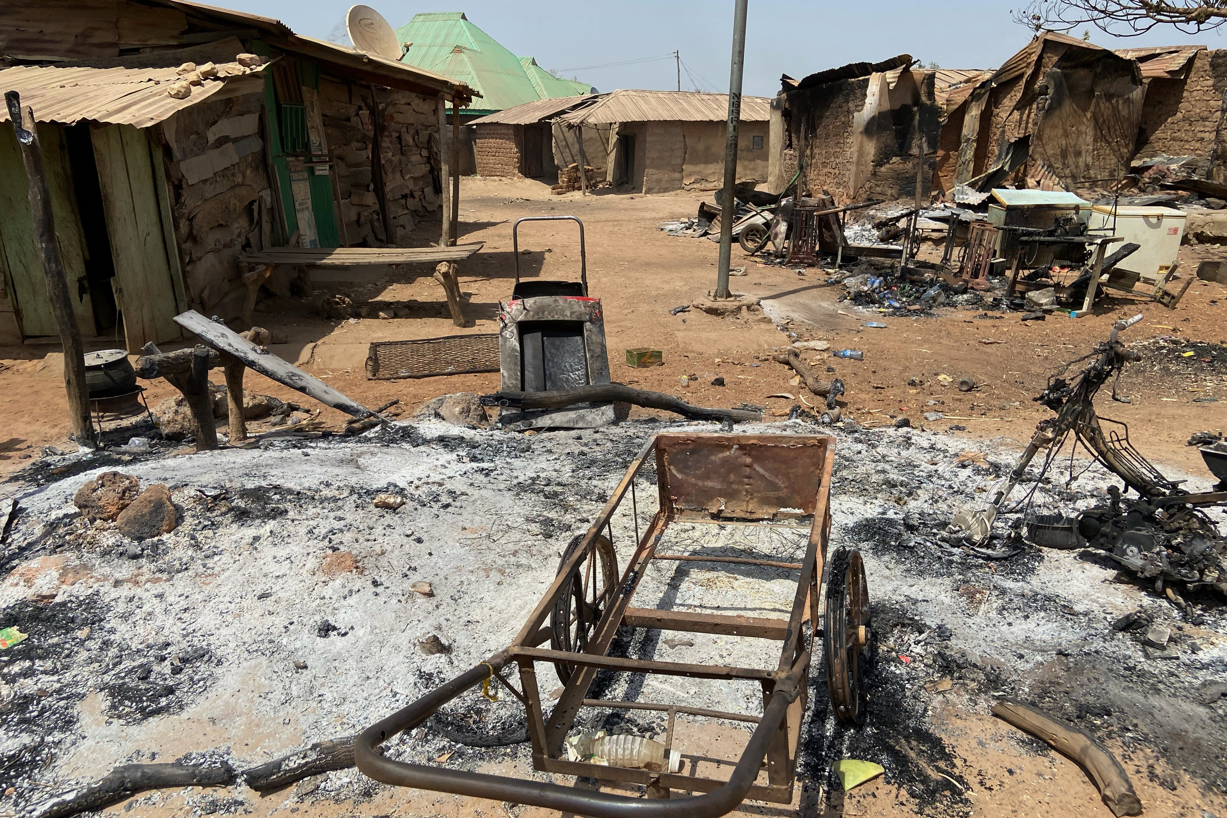 Burned homes and tools stand on an ash covered ground, days after an attack in the village of Woro, Nigeria.