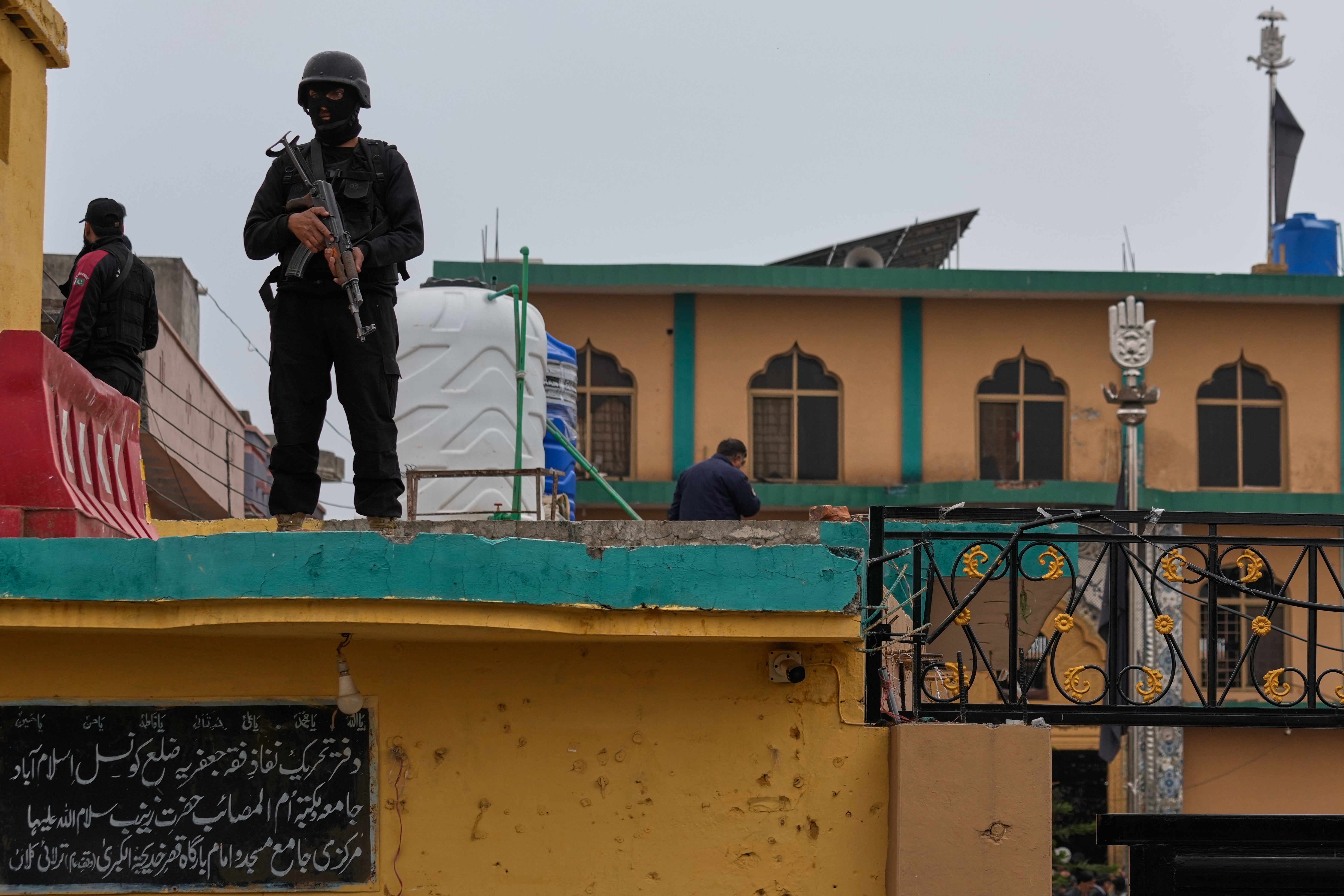 Police commandos take positions at the site of a bomb explosion at a Shiite mosque, in Islamabad, Pakistan.