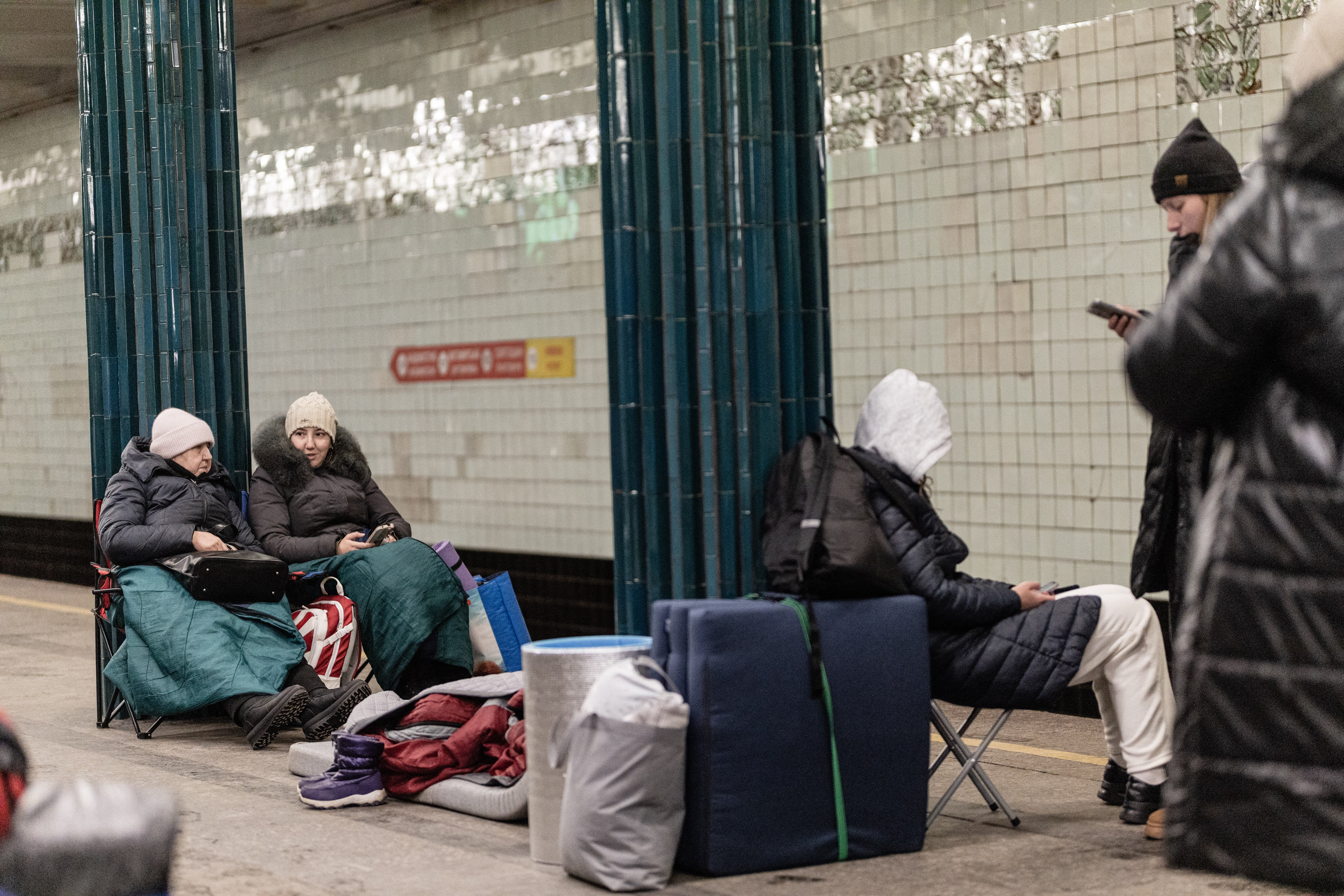 Women sit on folding chairs inside a metro station while taking shelter during the night, in Kyiv, Ukraine on February 7, 2026. Civilians used metro stations as temporary refuges with chairs, blankets, and sleeping bags to stay safe during overnight air attacks. (Photo by Daniel Yovkov / Hans Lucas / AFP via Getty Images)
