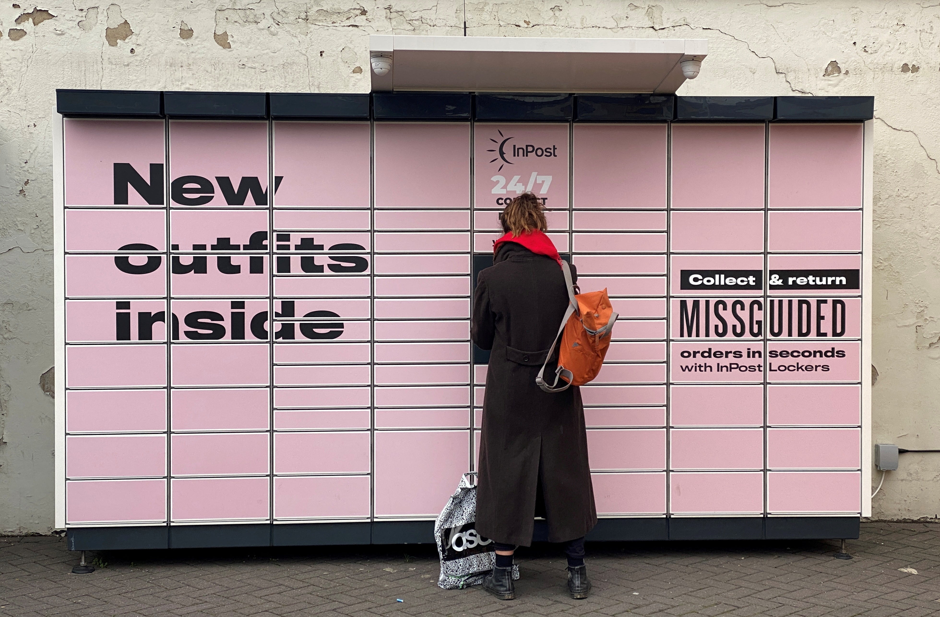 A woman stands at an InPost locker in Hackney, east London