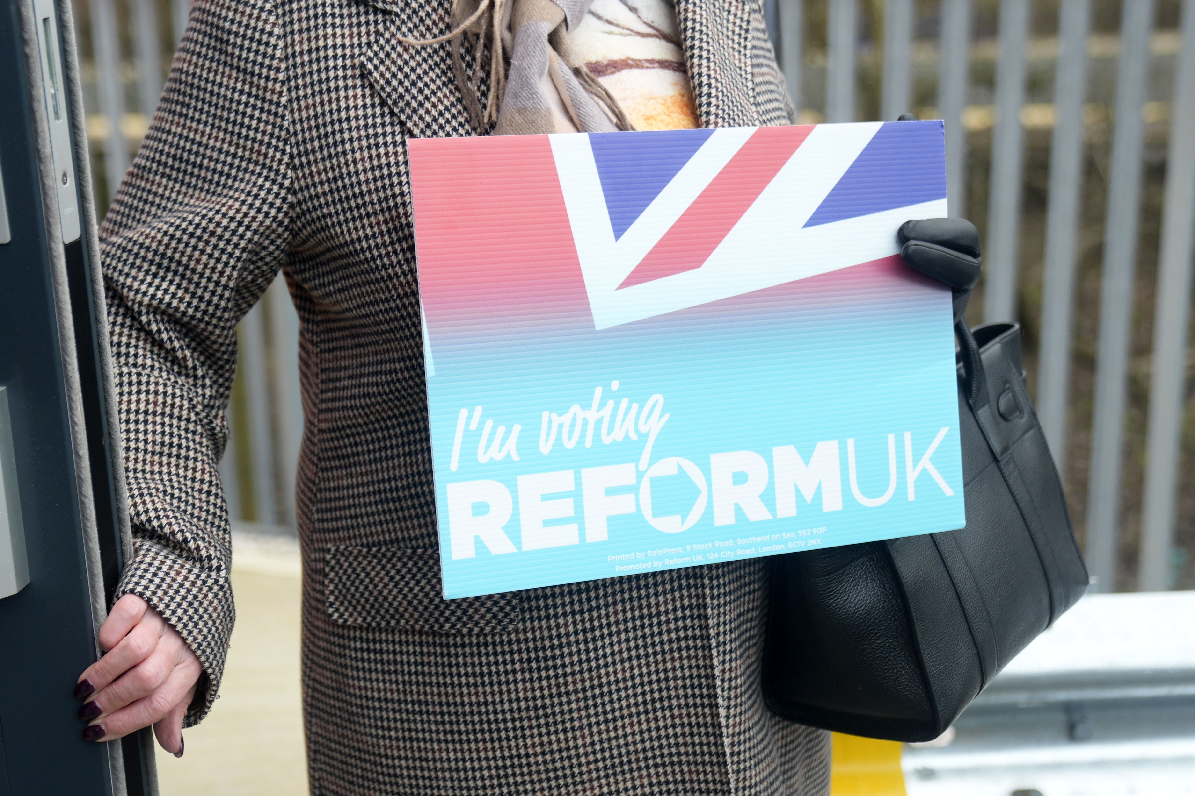A Reform UK supporter holding a placard at the party’s Gorton and Denton by-election headquarters