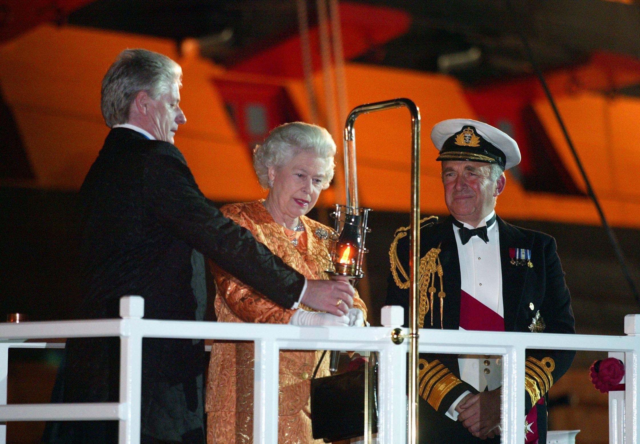 First Sea Lord Admiral Sir Alan West, right, looks on as Bruno Peek helps Britain's Queen Elizabeth II to light the Trafalgar Weekend Beacon during her visit to Nelson's flagship HMS Victory in Portsmouth in 2005