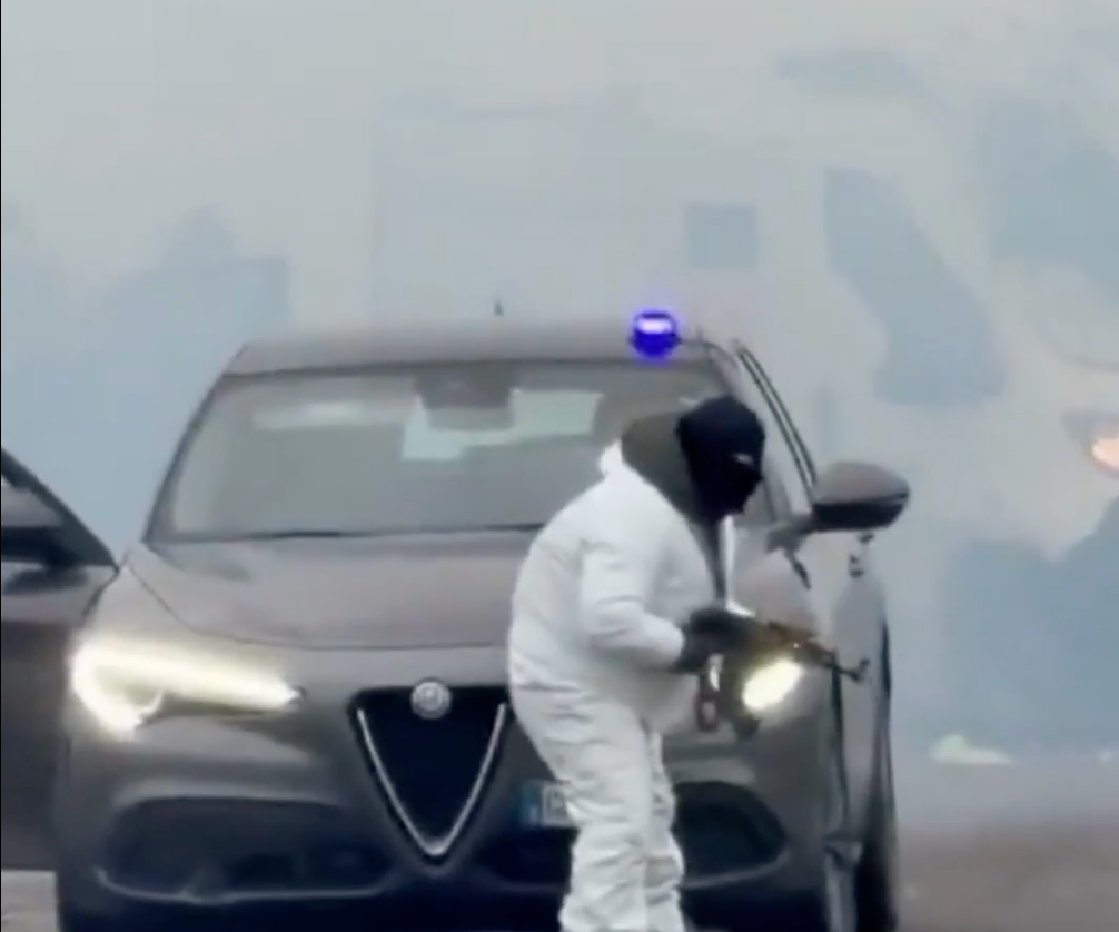 A man in white overalls keeps watch with a gun while his accomplices appear to unload the van during the robbery