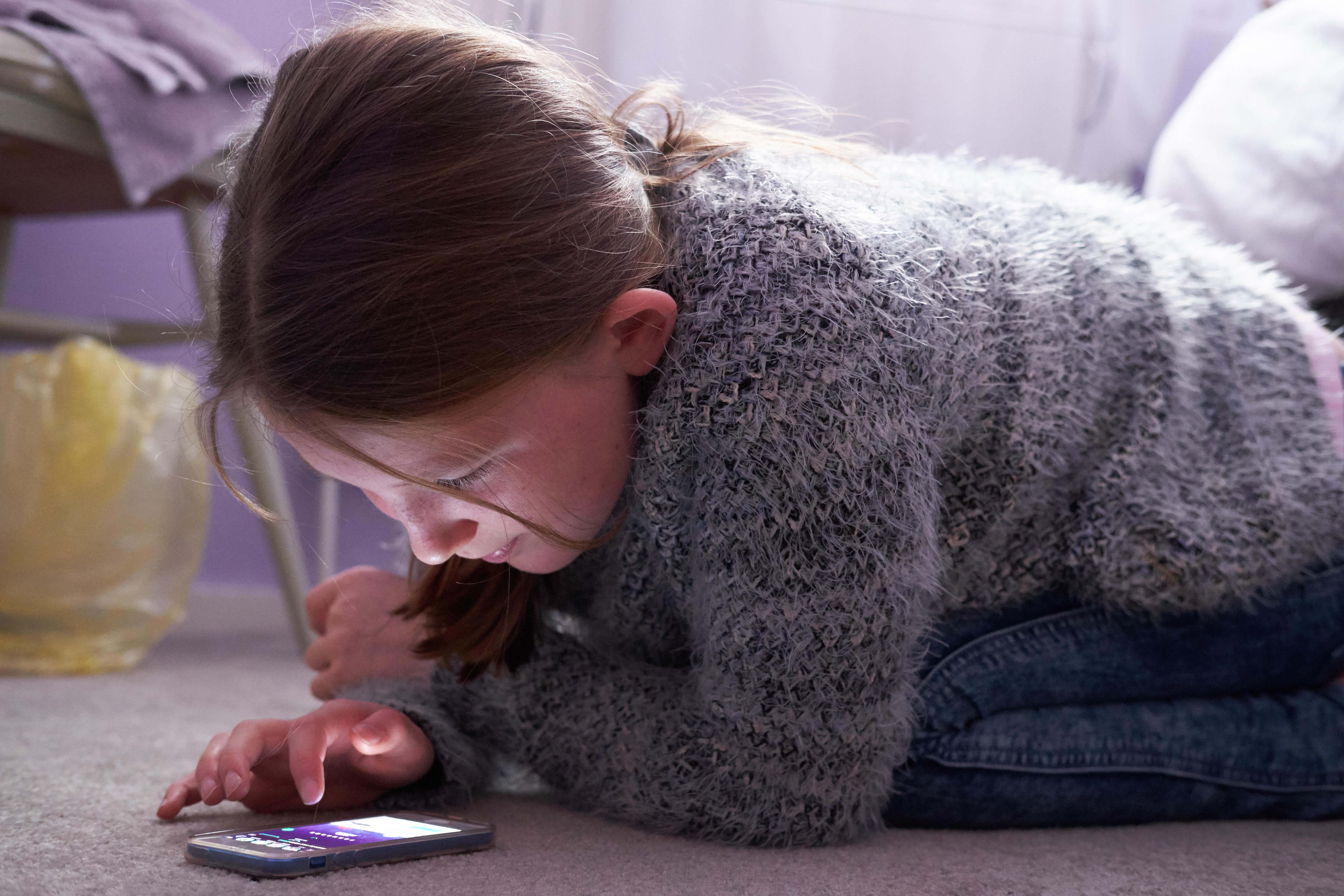 A young girl looking at her mobile phone (Alamy/PA)