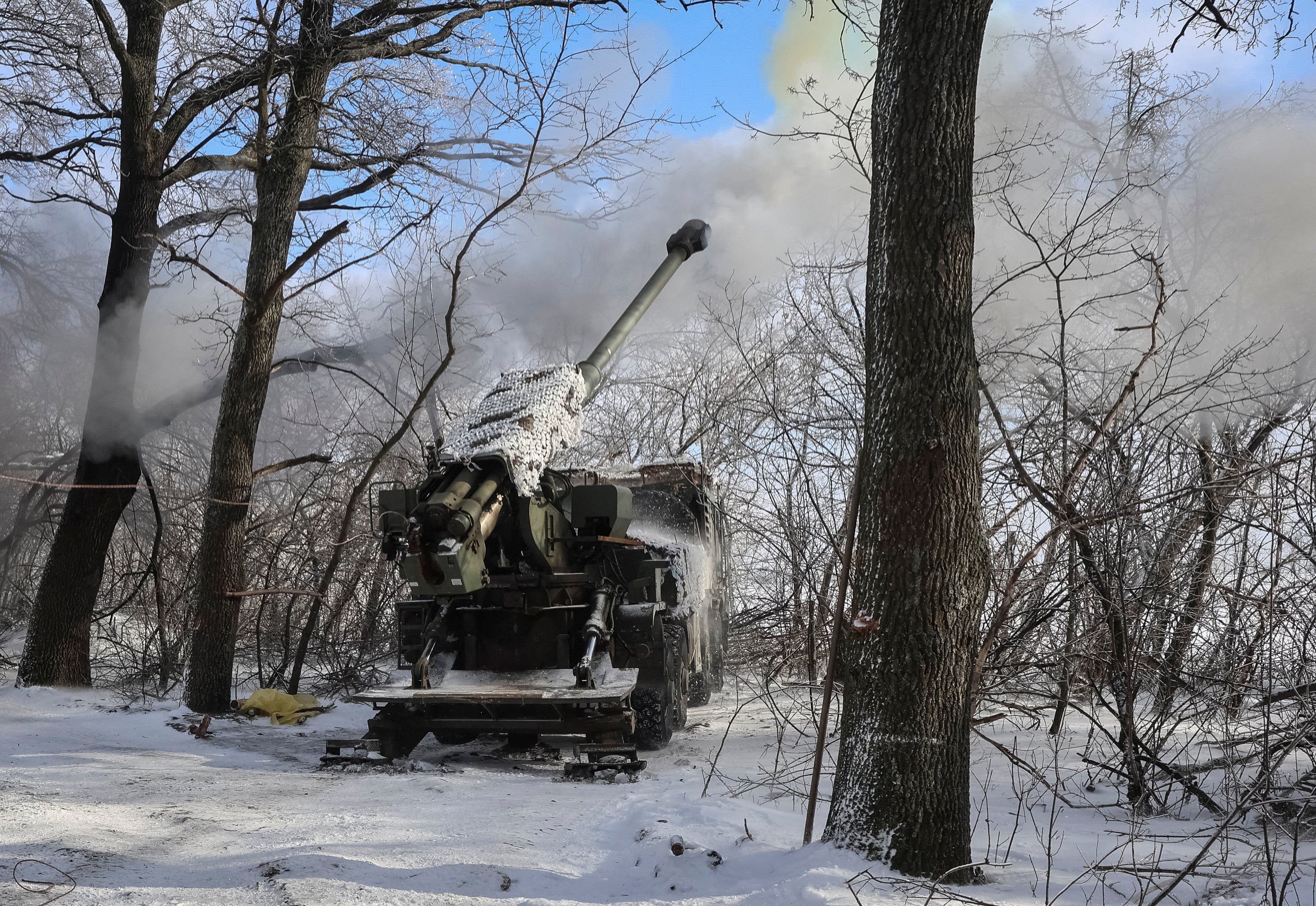 Ukrainian soldiers fire a self-propelled howitzer towards Russian troops