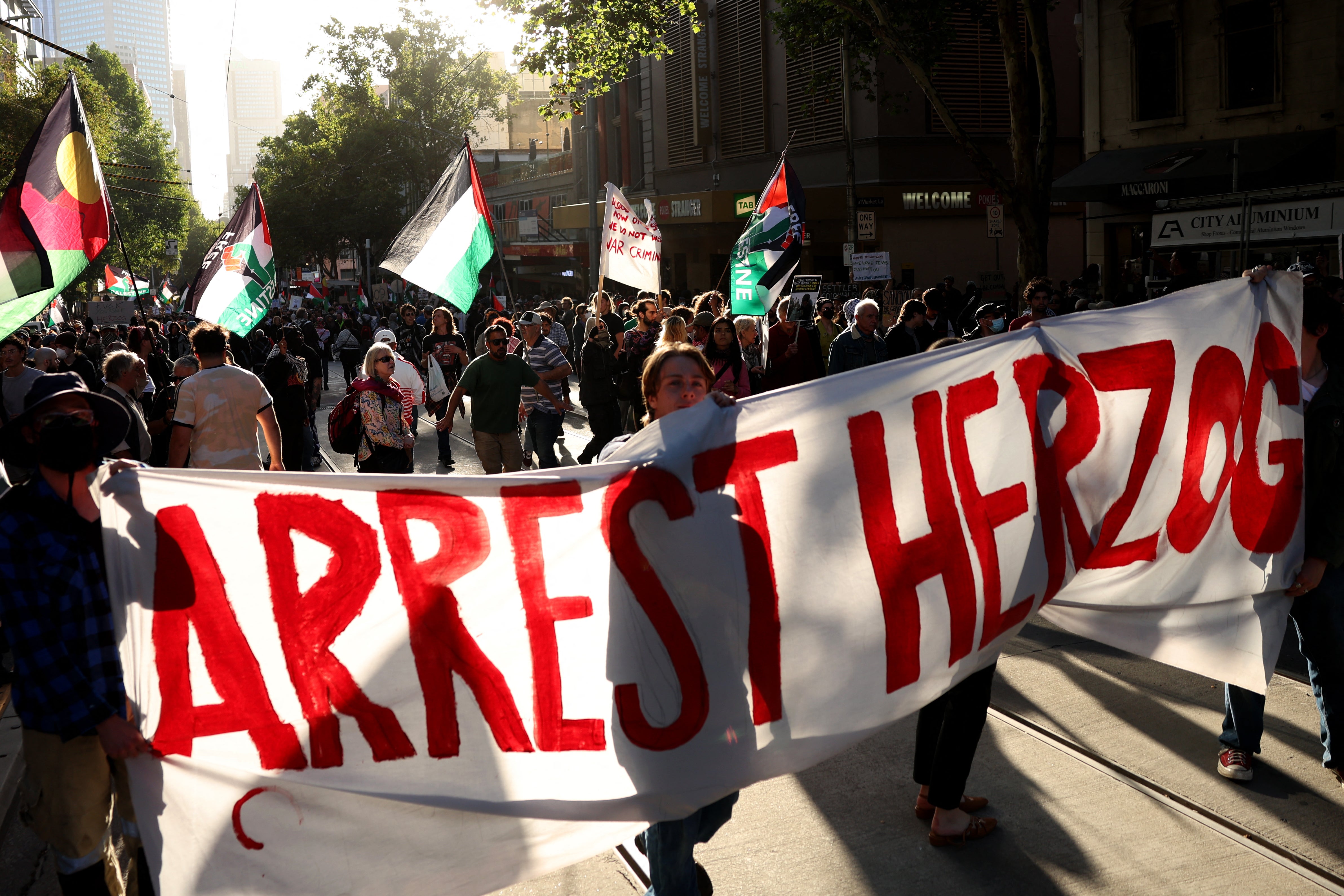 Protesters hold placards and flags as they march during the visit of Israel’s president, Isaac Herzog, in Melbourne on 12 February 2026. Herzog’s tightly secured, four-day trip aims to console Australia’s Jewish community after the December shooting at Sydney’s Bondi Beach that killed 15 people at a Hanukkah festival