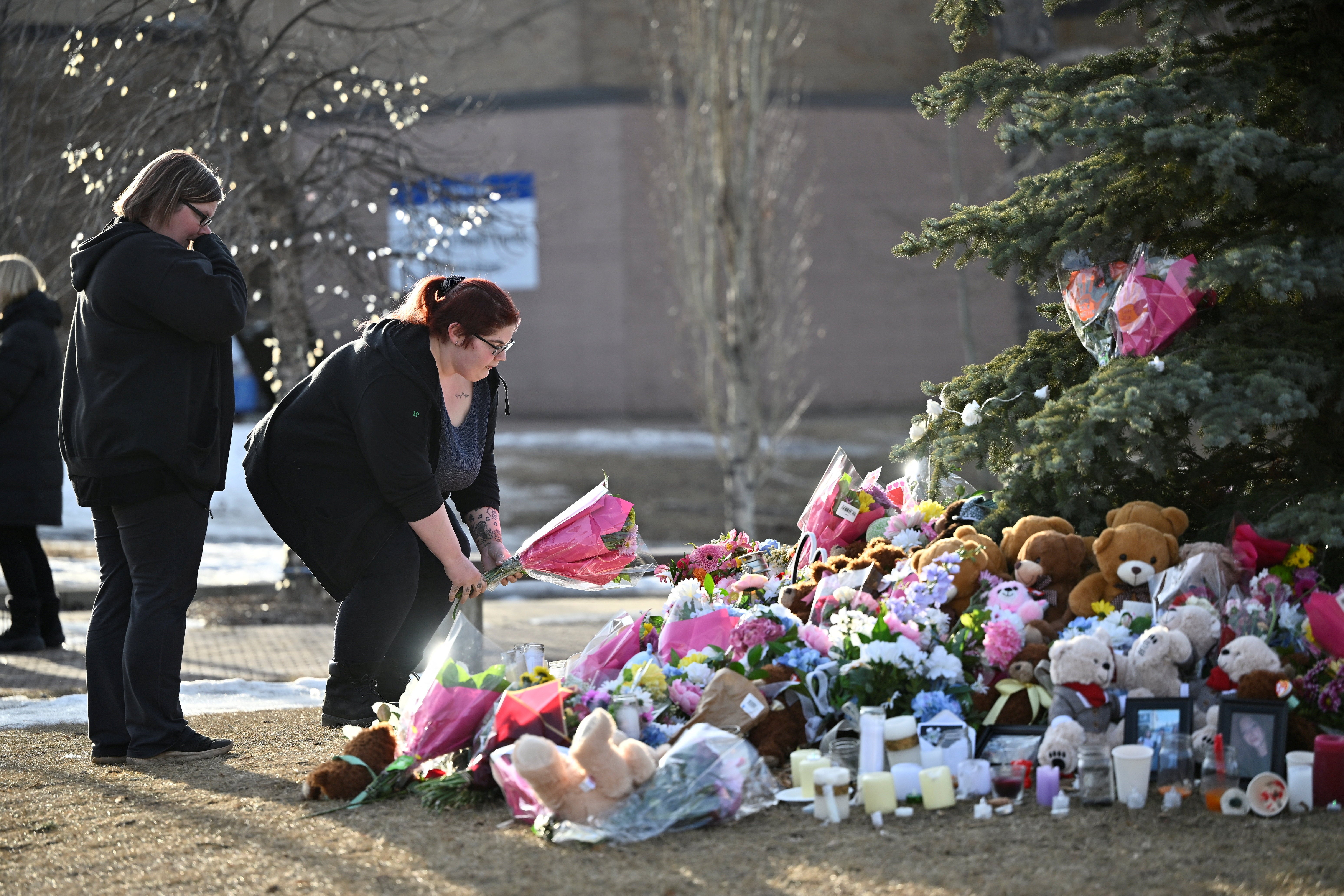 A woman places flowers at a makeshift memorial for the victims two days after a deadly mass shooting took place at a school, in the town of Tumbler Ridge, British Columbia, Canada February 12, 2026