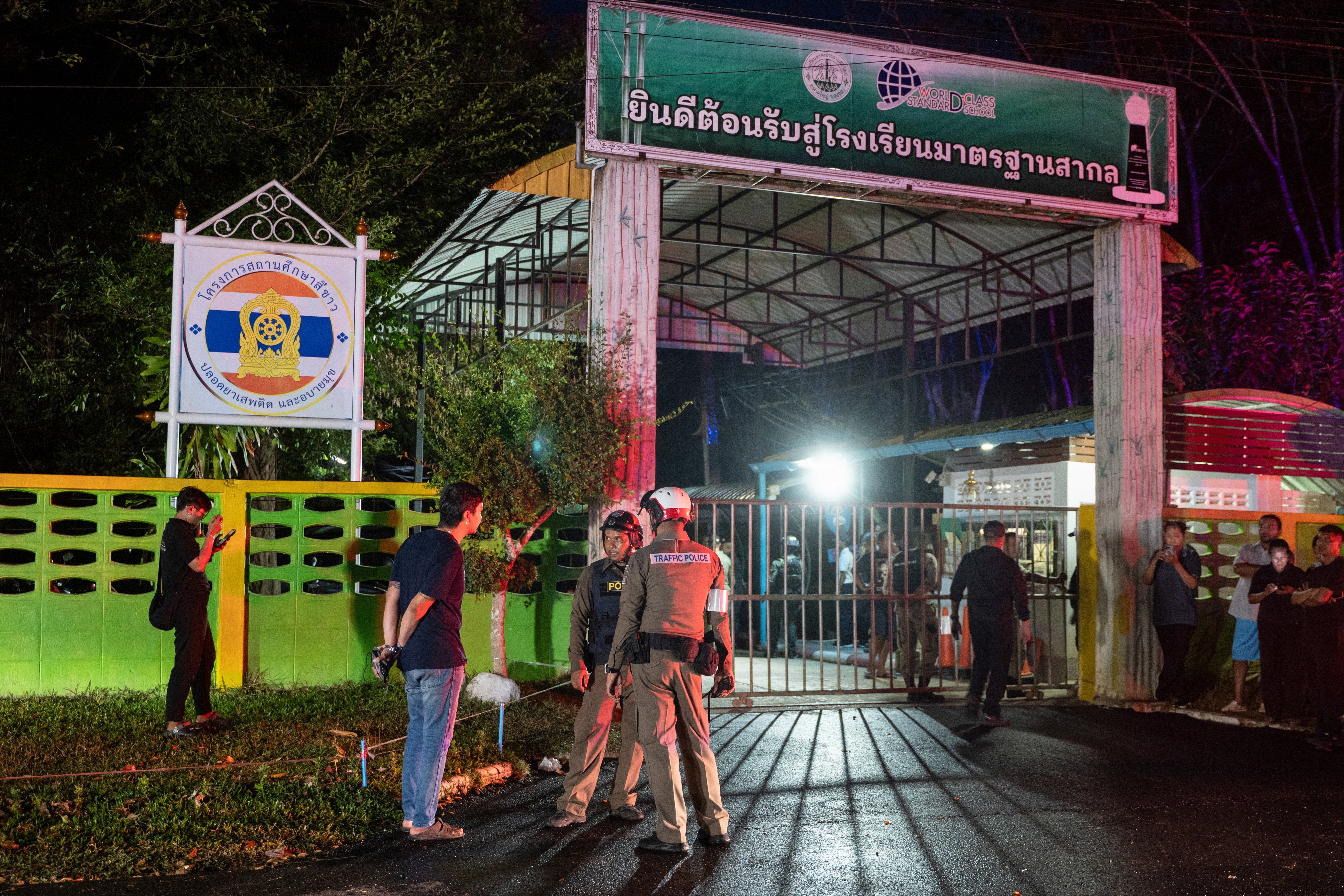 Police officers and people stand near the gate of Patongprathankiriwat School, following an incident in which a gunman entered the school and held an unknown number of students and teachers hostage, in southern Thailand’s Songkhla, Thailand, 11 February 2026