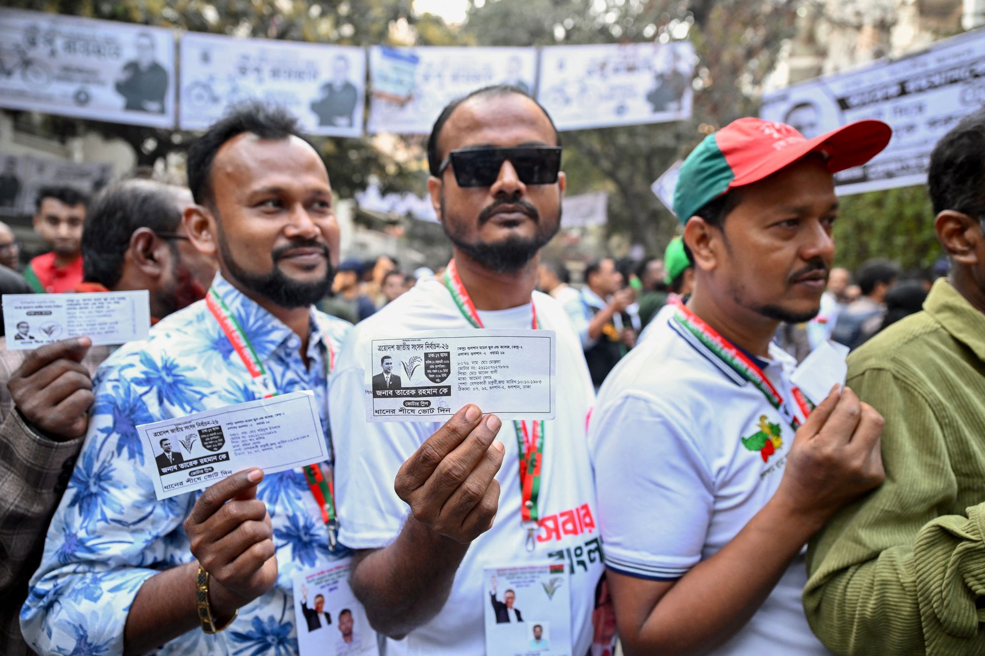 Voters show their voter slips as they wait in a queue to cast their ballots at a polling station during Bangladesh's general election in Dhaka on February 12, 2026