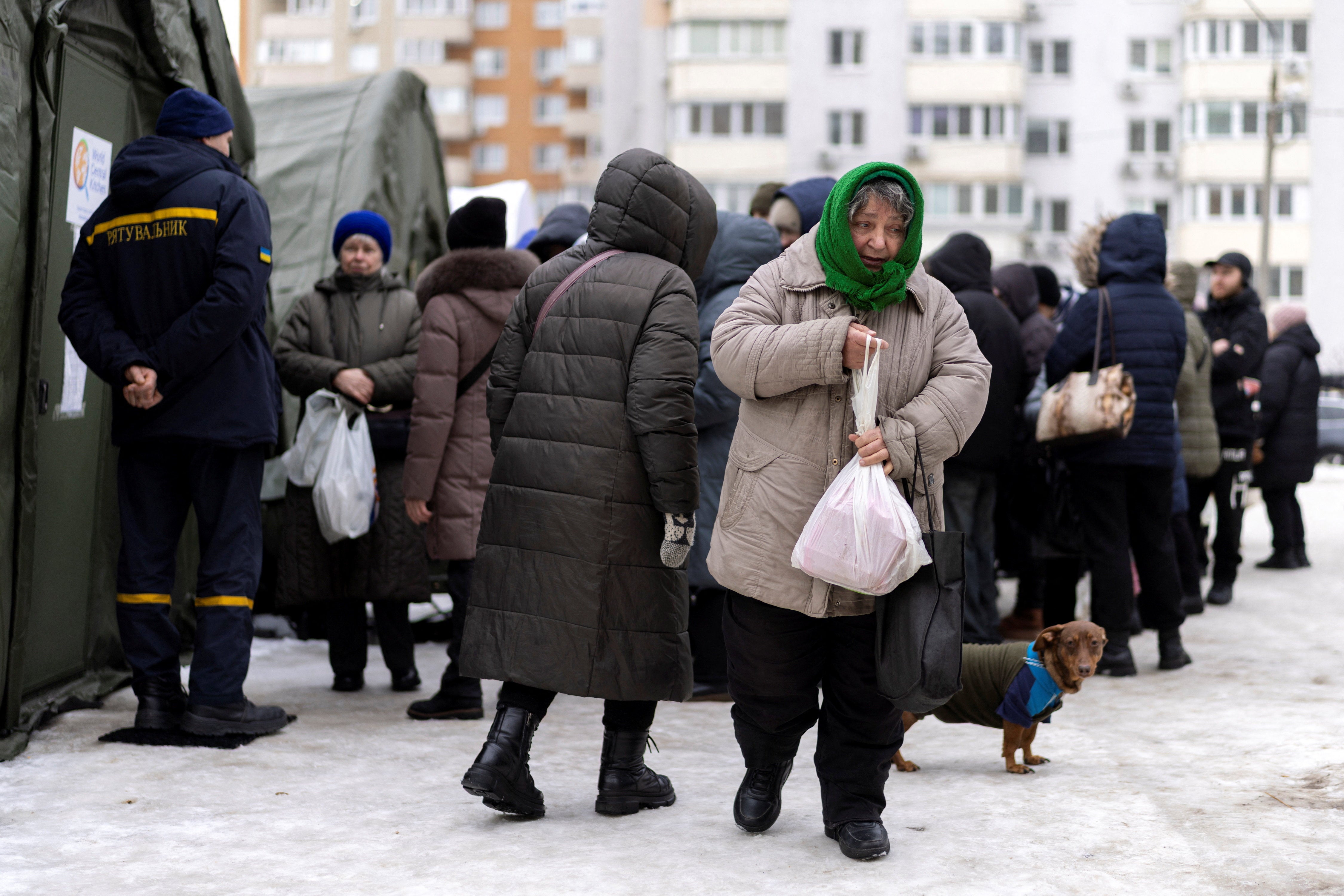 A woman carries a free warm meal that she received at a heated tent of the emergency services