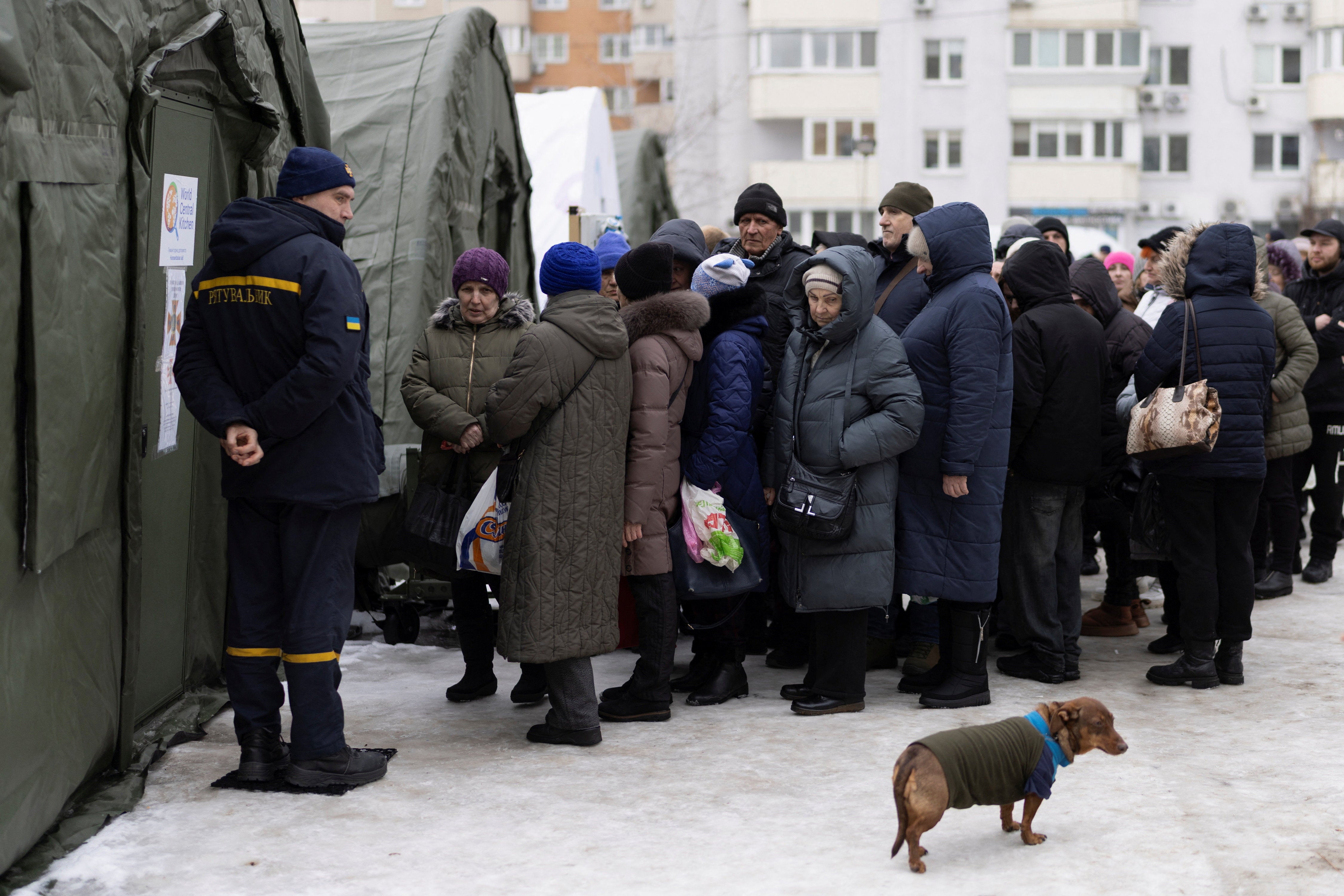 People line up for a free warm meal at a heated tent of the emergency services in a neighbourhood where many apartments are left without electricity