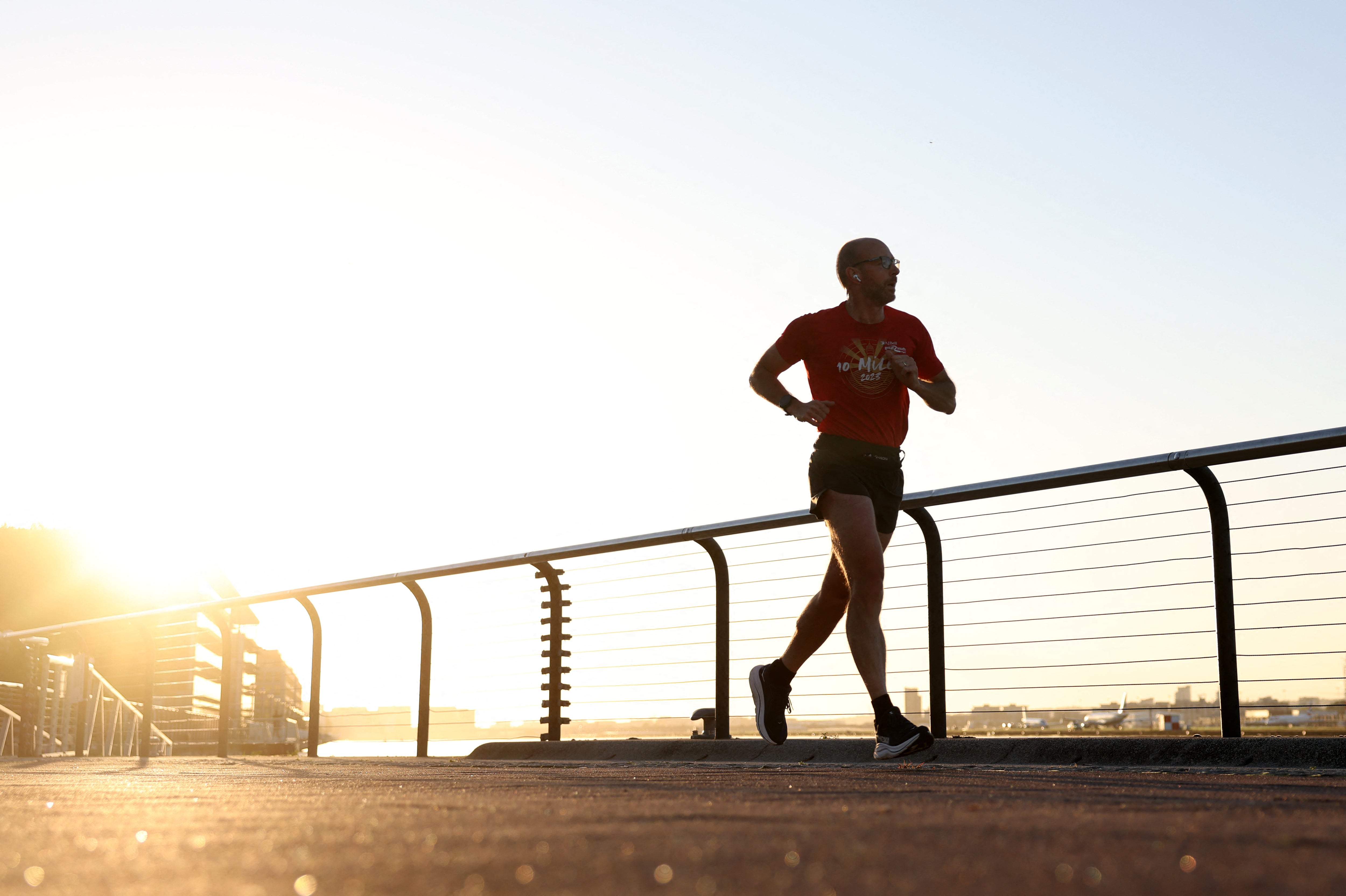 A jogger runs along the dock side, just after sunrise, in east London