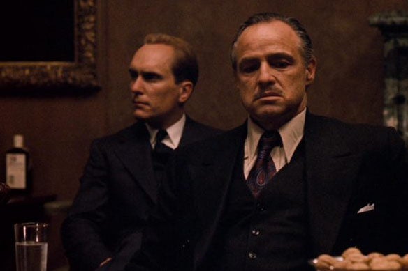 Robert Duvall seated behind Marlon Brando in ‘The Godfather’