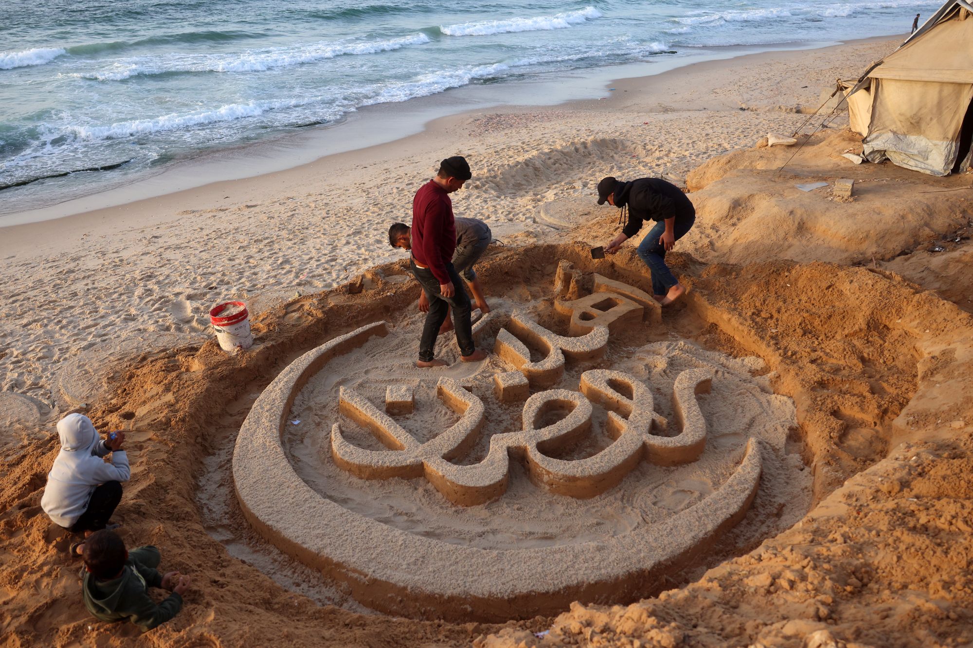 Palestinian artist Yazeed Abu Jarad creates a sand sculpture with the message ‘Welcome Ramadan’ in Khan Yunis