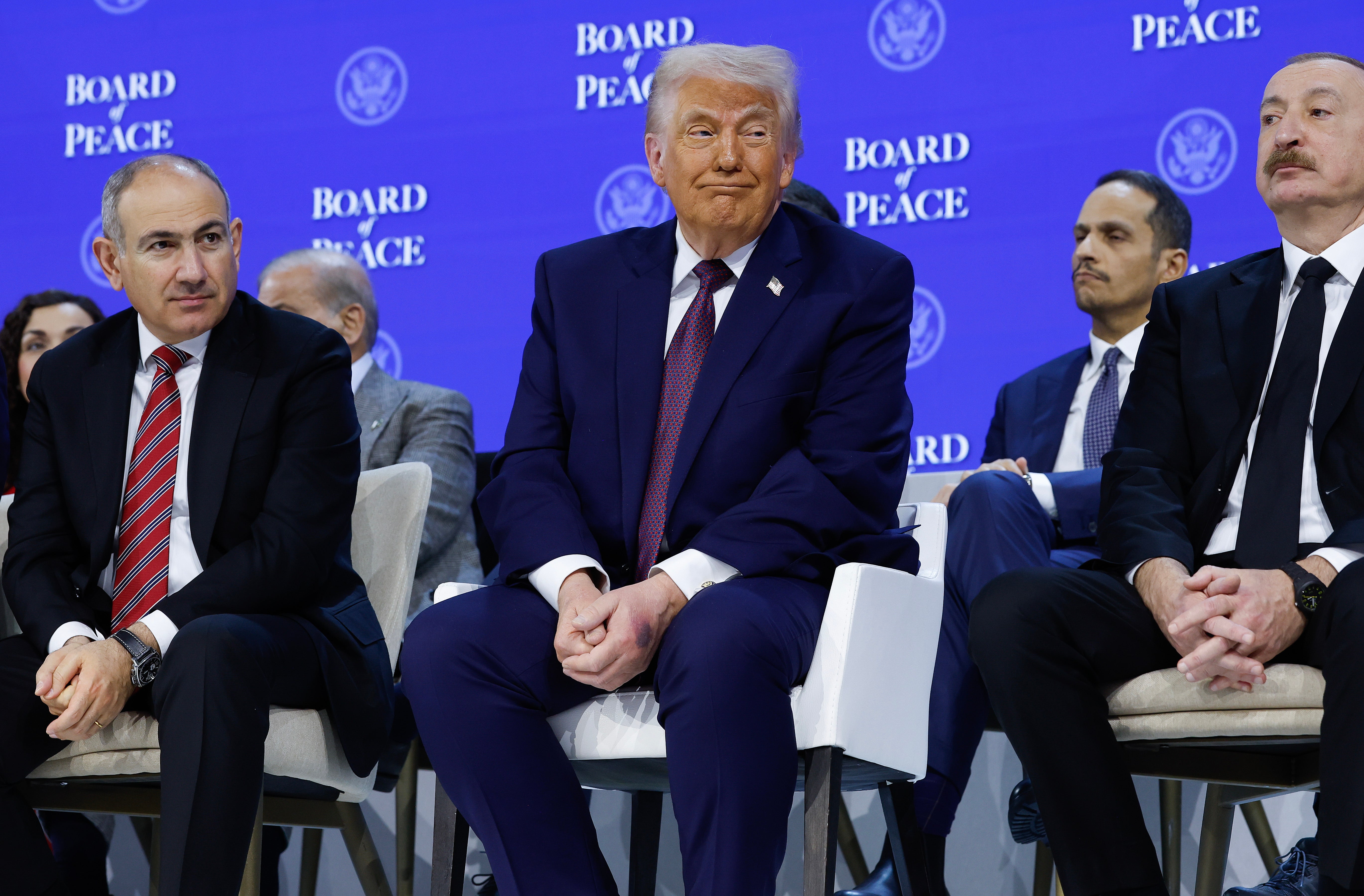President Donald Trump (C) sits in between Prime Minister of Armenia Nikol Pashinyan (L) and Azerbaijan President Ilham Aliyev during a signing ceremony for the Board of Peace at the World Economic Forum (WEF)