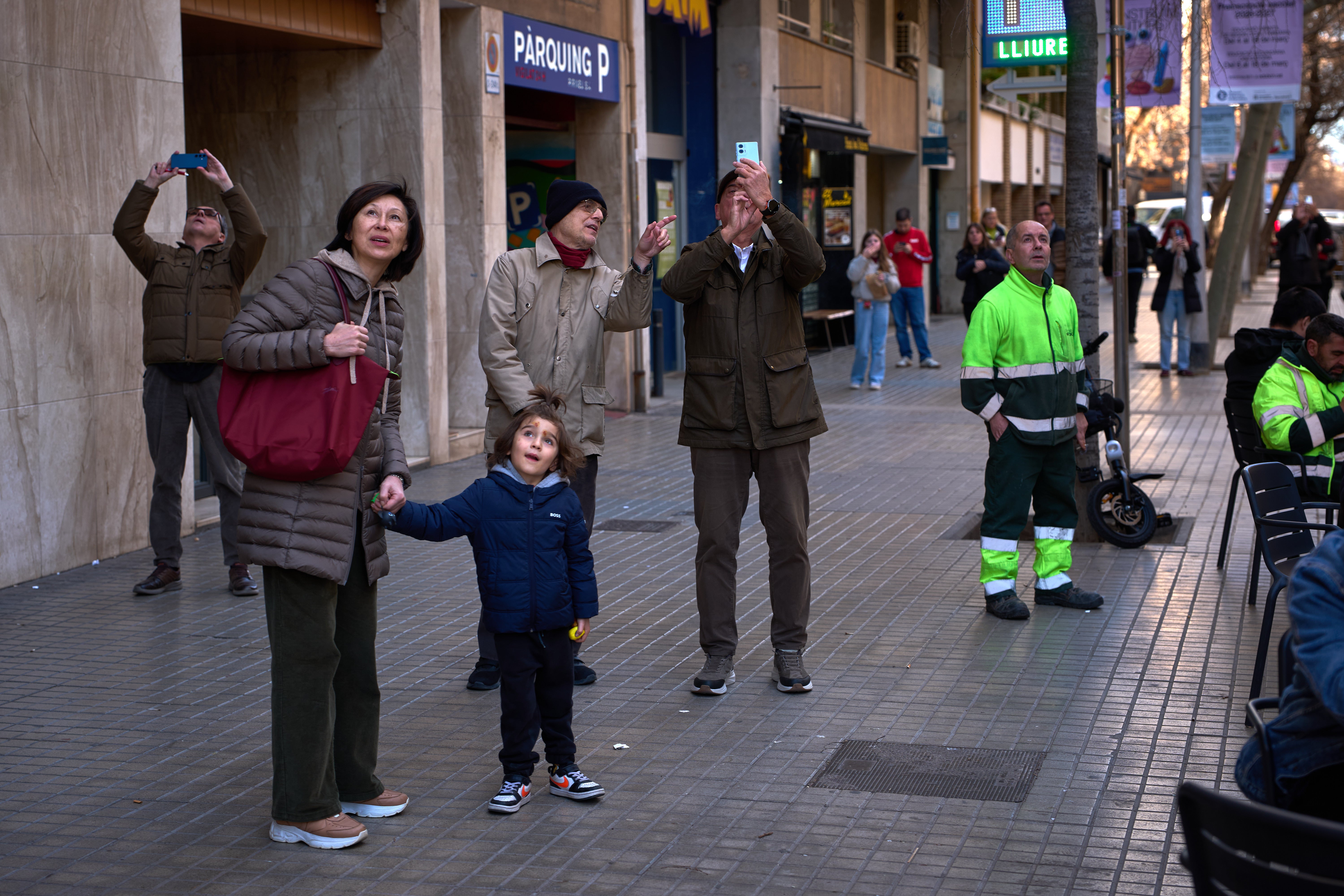 People watch as a crane lifts the upper arm of the cross onto the Tower of Jesus Christ at the Sagrada Familia in Barcelona, Spain.