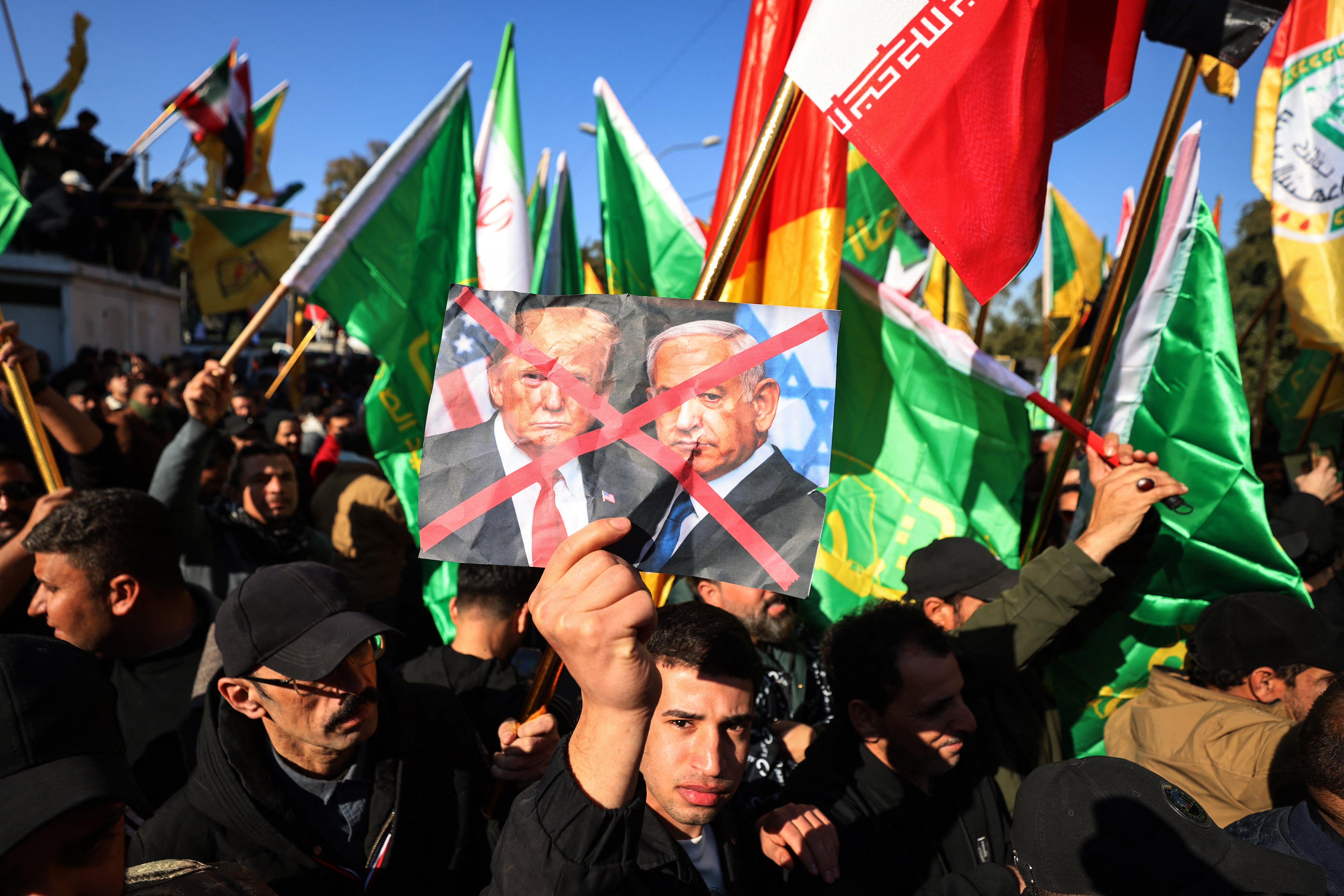A protester holds up crossed out portraits of US President Donald Trump and Israeli Prime Minister Benjamin Netanyahu during a demonstration near the Iranian embassy in Baghdad last month against Israel and recent US threats of military action in Iran, and in support of the Iranian regime and its supreme leader