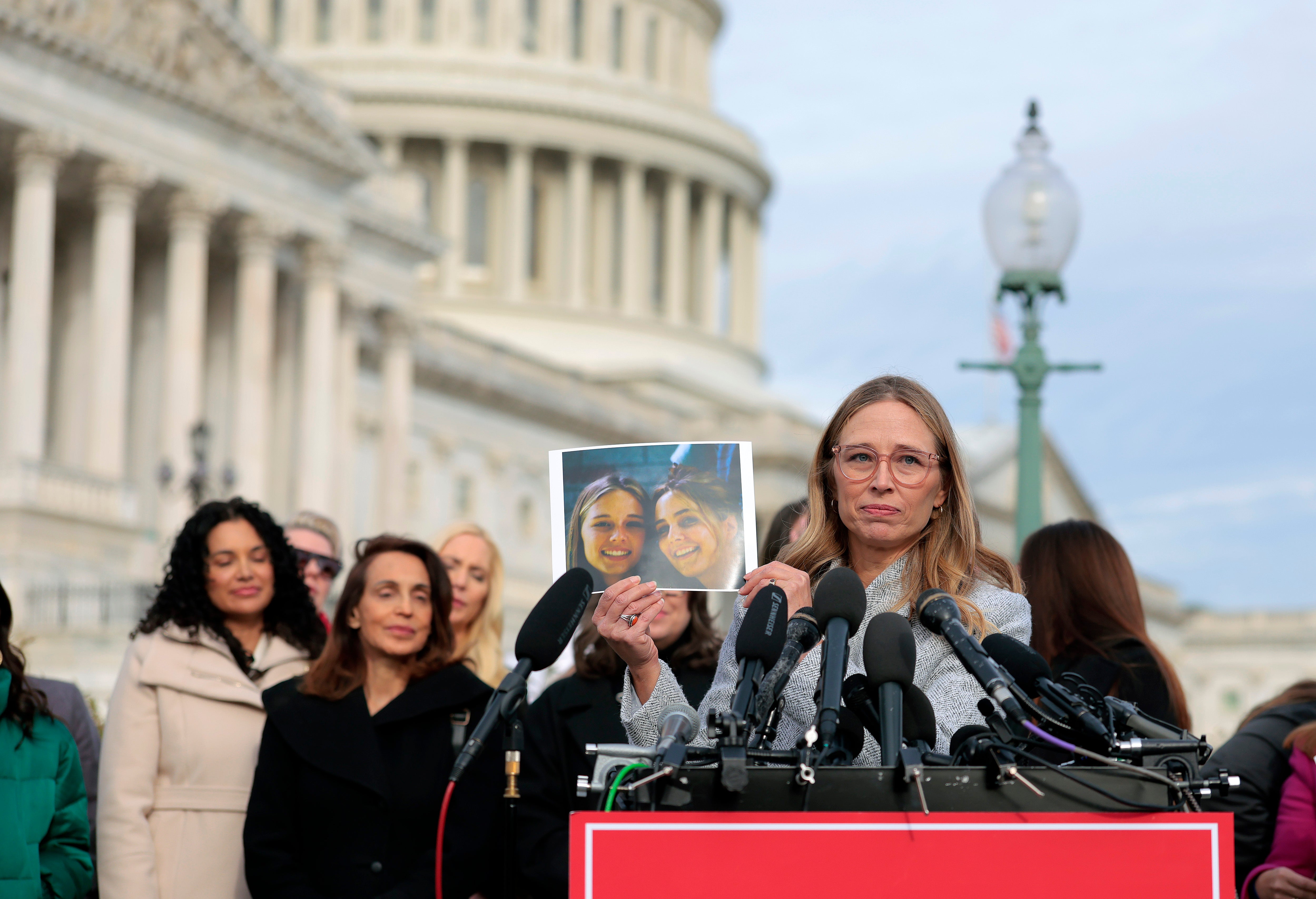 Epstein accuser Annie Farmer holds up a picture of herself and sister Maria, who also accused Epstein of trafficking her