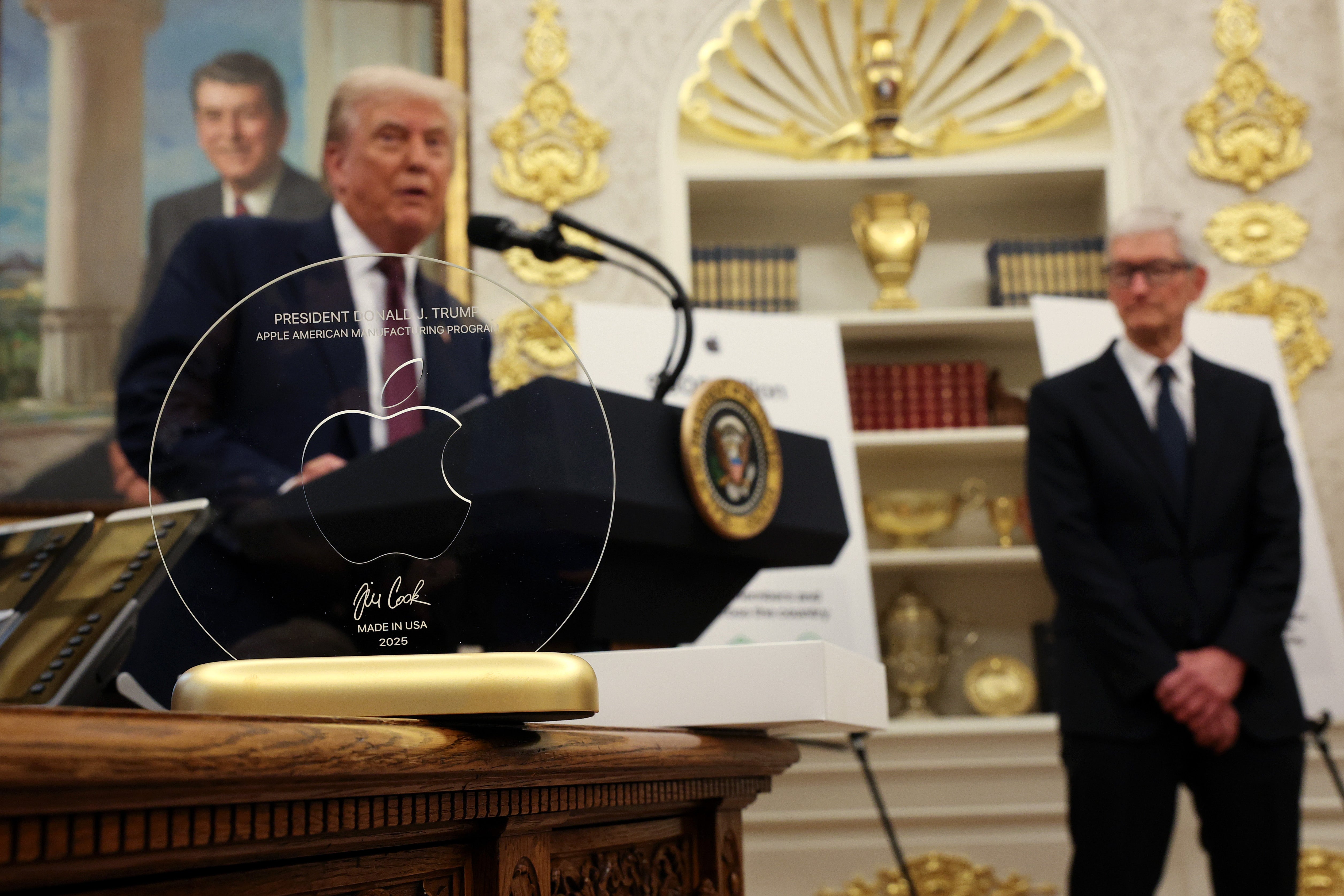 President Donald Trump speaks behind an engraved glass disc gifted to him by Apple CEO Tim Cook during an event in the Oval Office of the White House last year