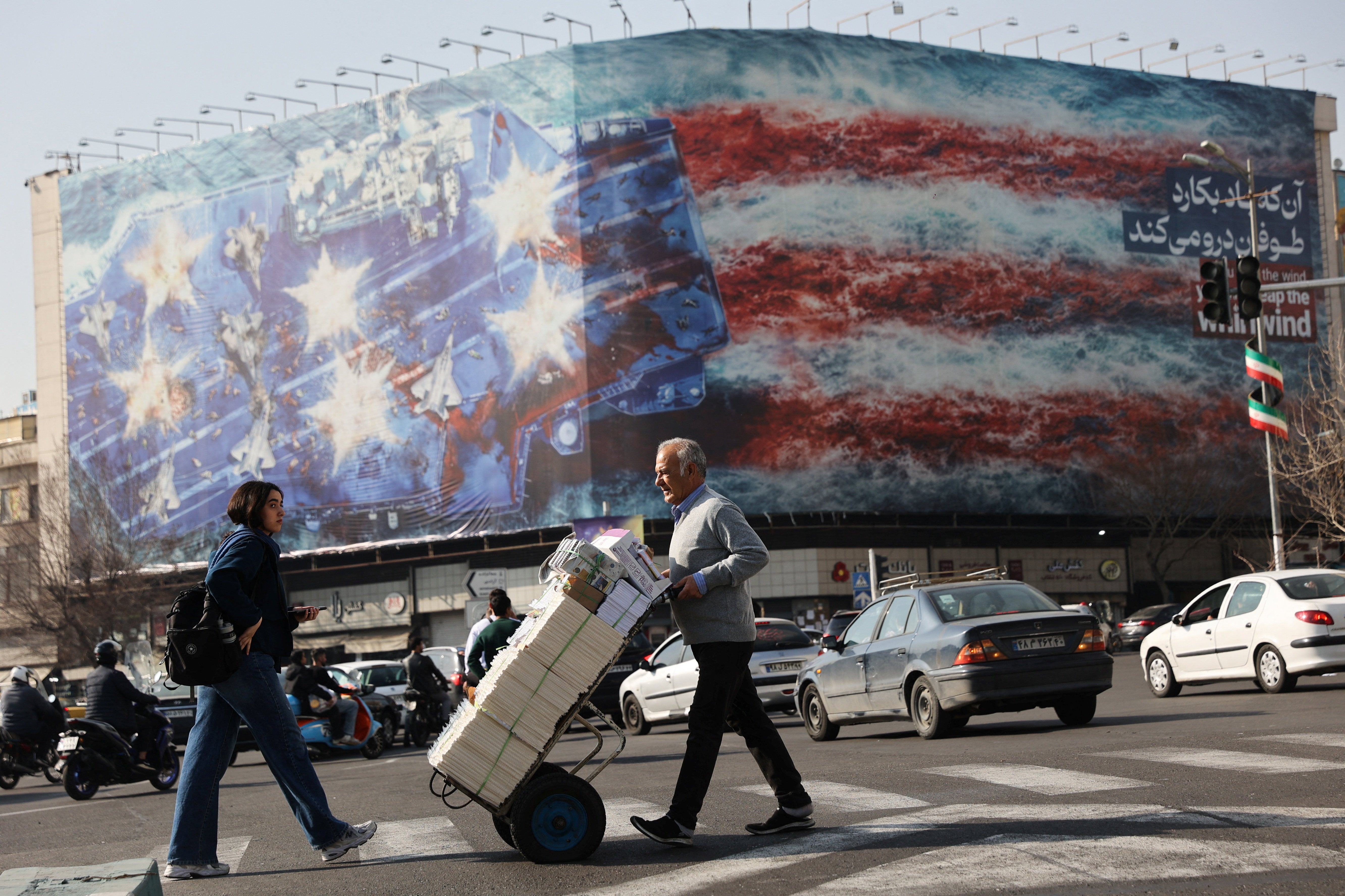 People walk past an anti-U.S. billboard in Tehran, Iran, February 19, 2026