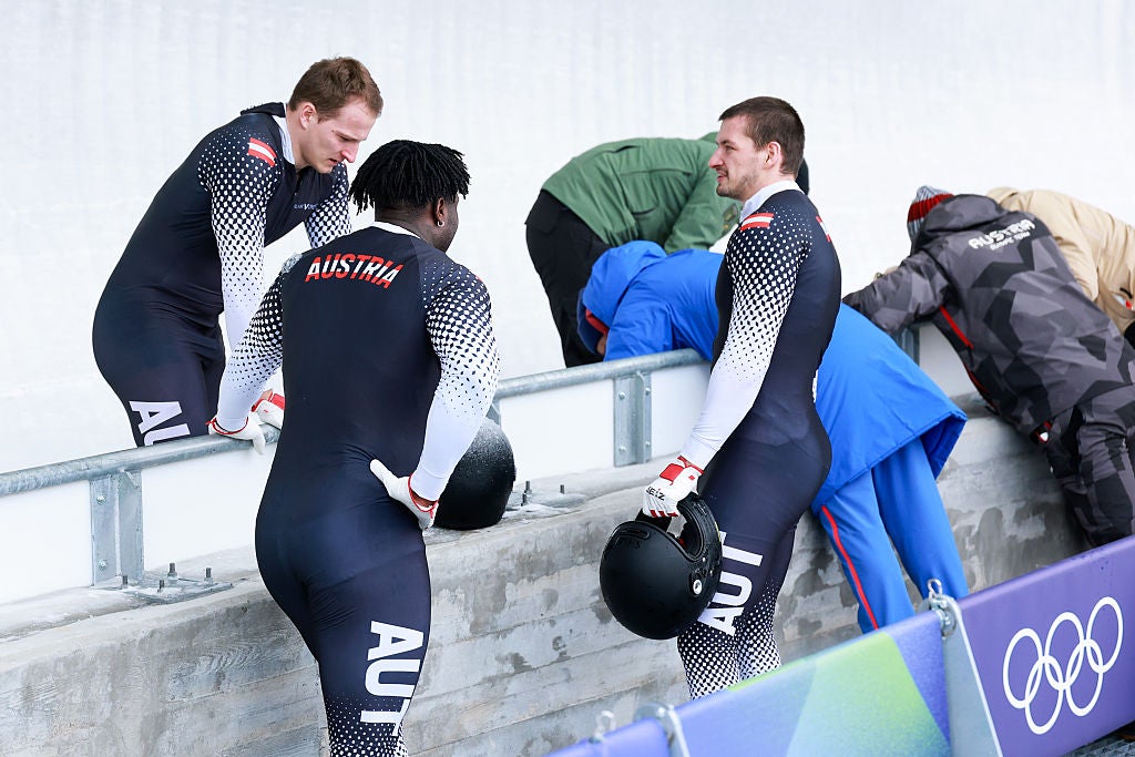 Daniel Bertschler, Sebastian Mitterer and Daiyehan Nichols-Bardi of Team Austria wait as officials gather for the medical treatment for pilot Jakob Mandlbauer