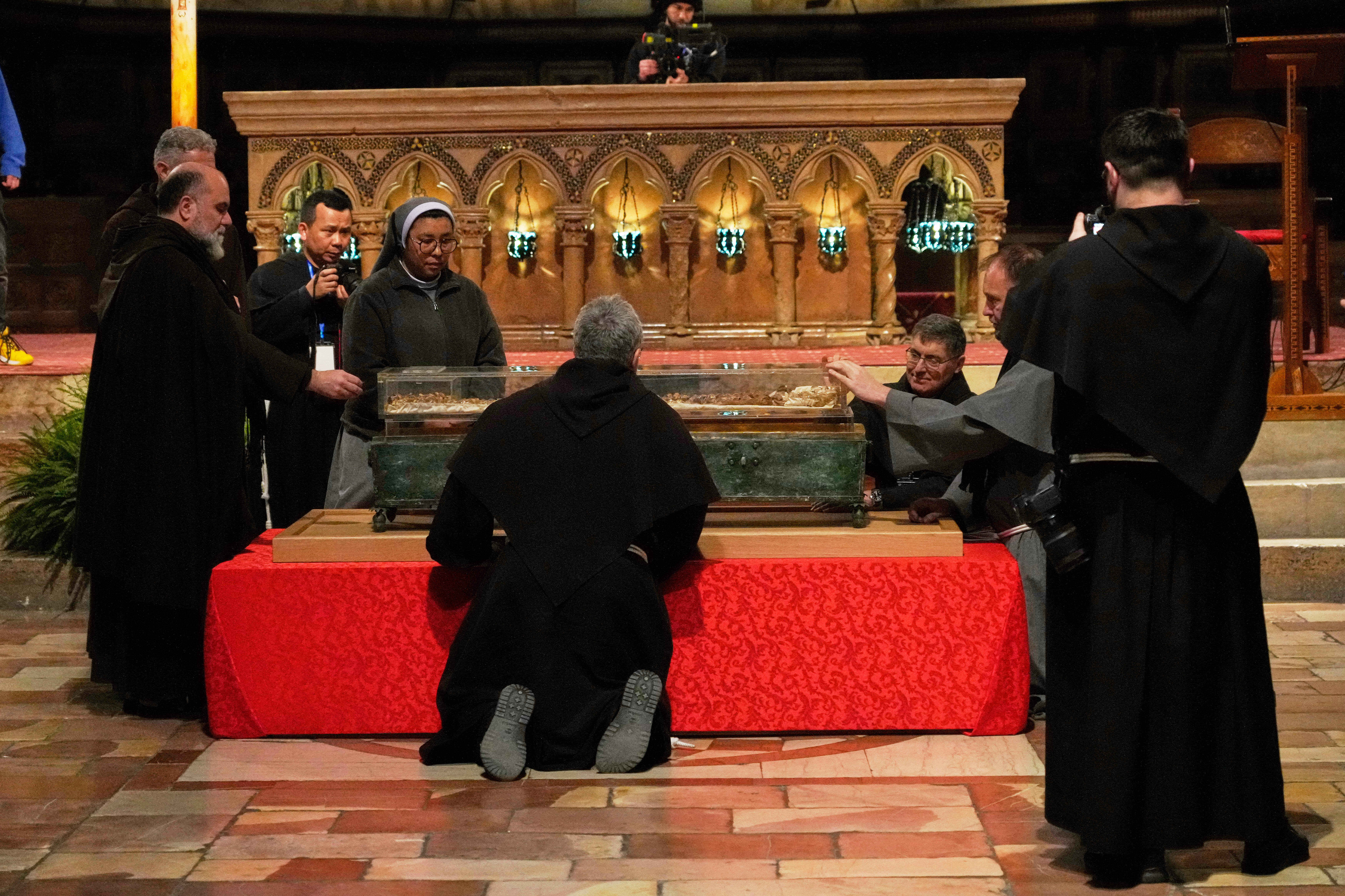 Friars and a nun pray before the remains of Francis of Assisi