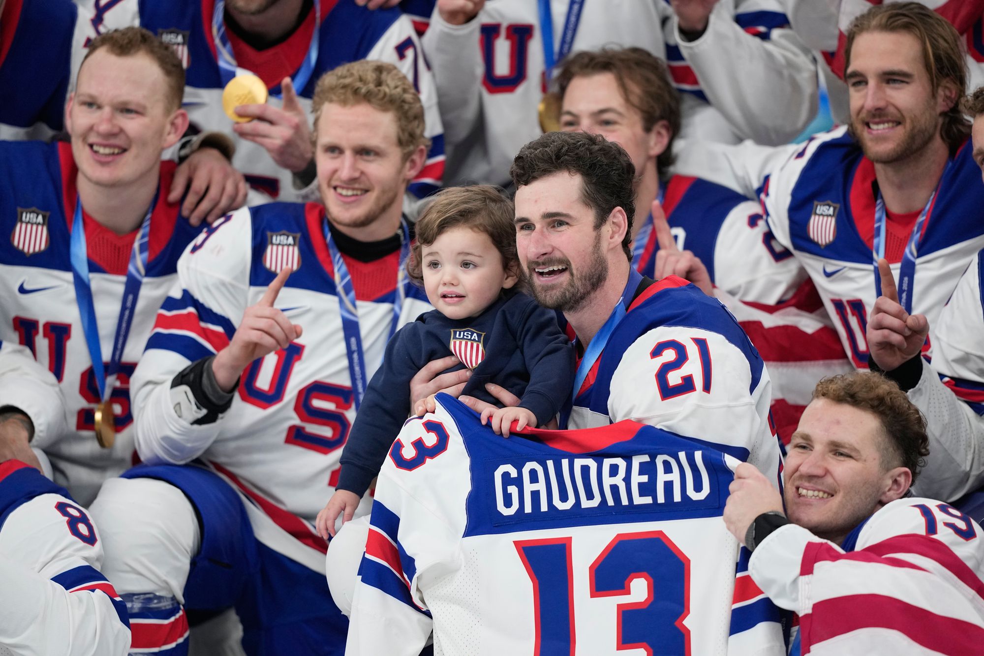 USA players hold the shirt of the late Johnny Gaudreau with his son, Johnny Jr, after beating Canada
