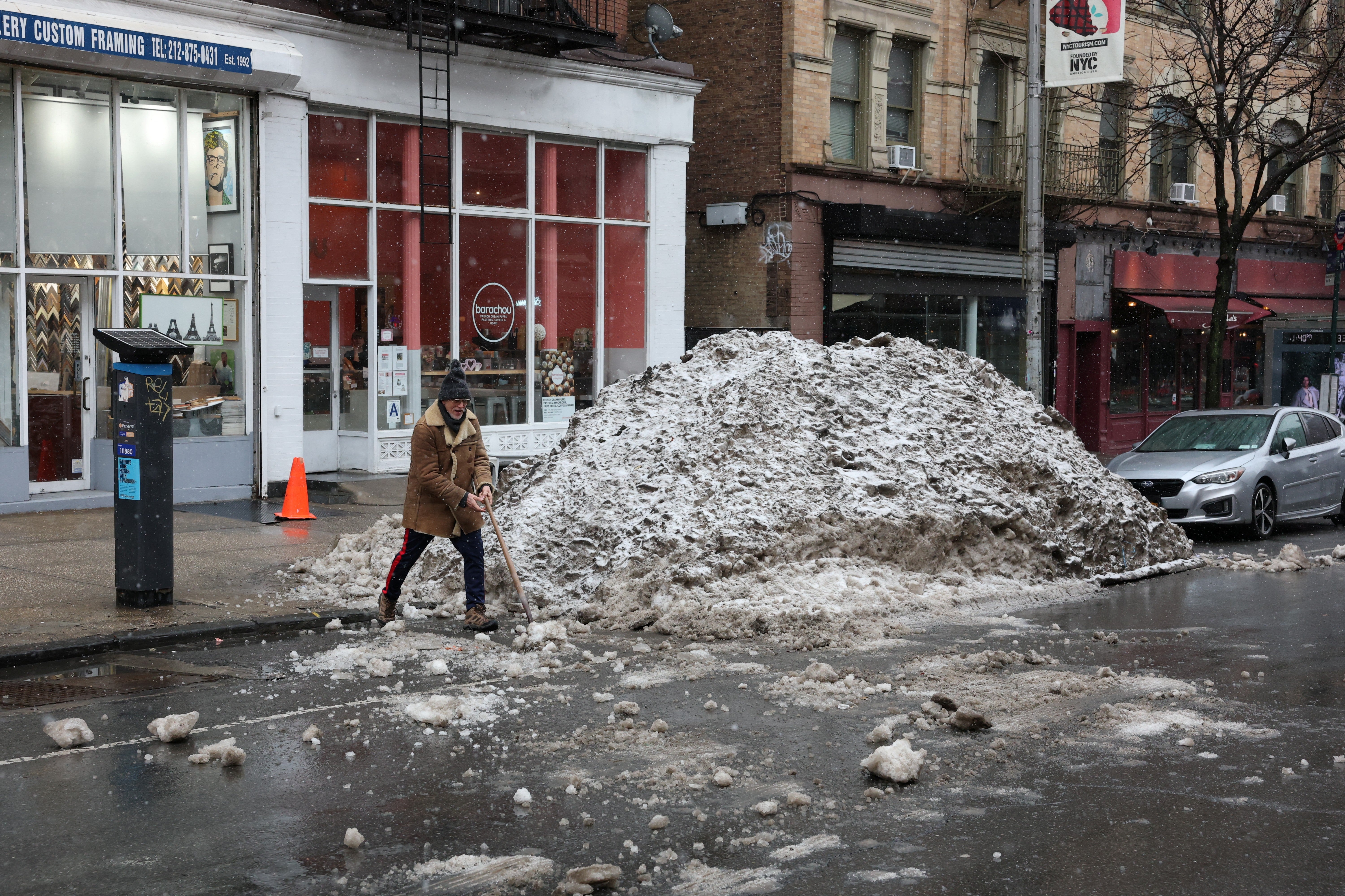 A man shovels a pile of snow ahead of the winter storm in New York